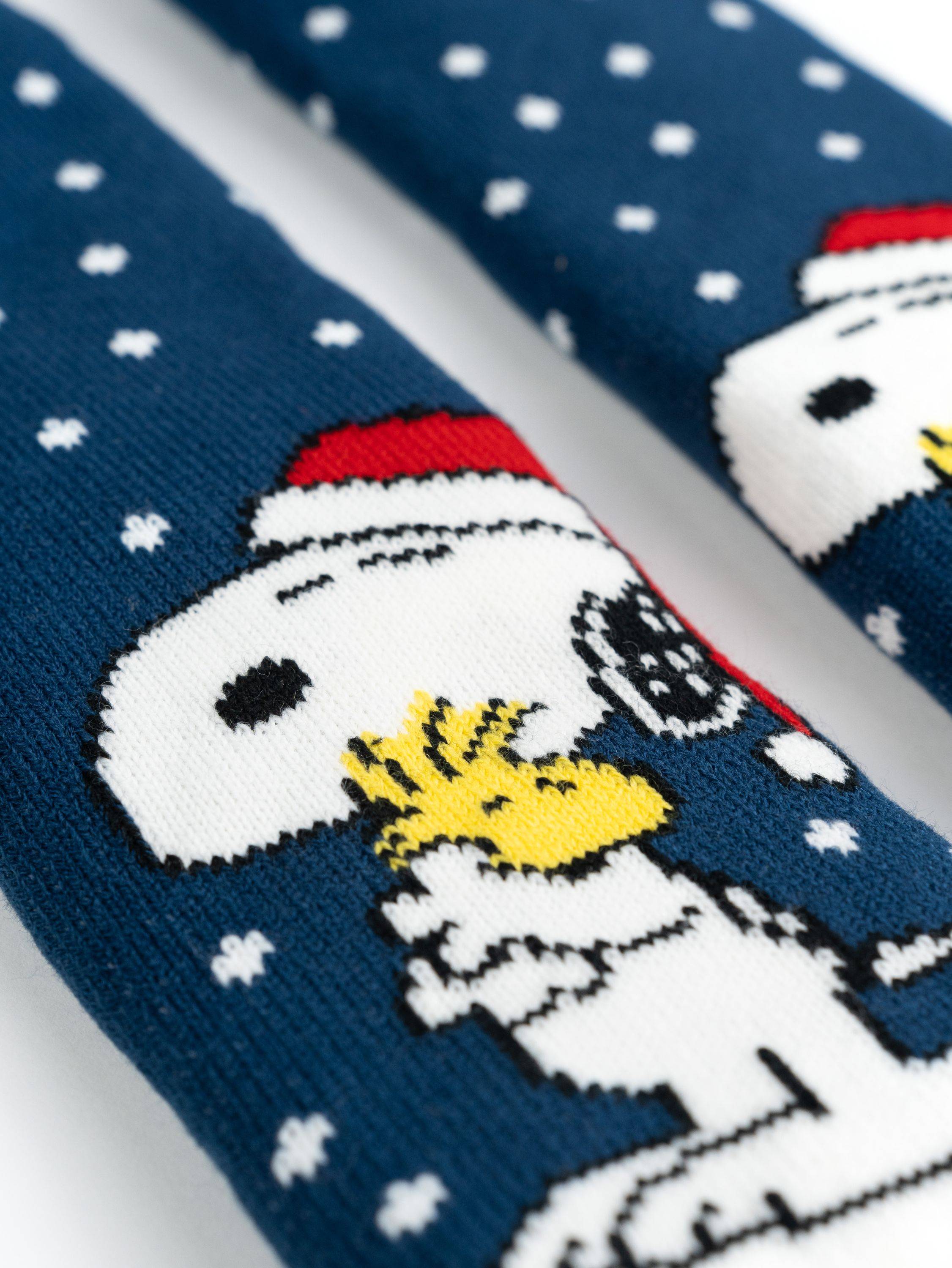 Socken mit Snoopy mit Weihnachtsmütze und weißen Schneeflocken.