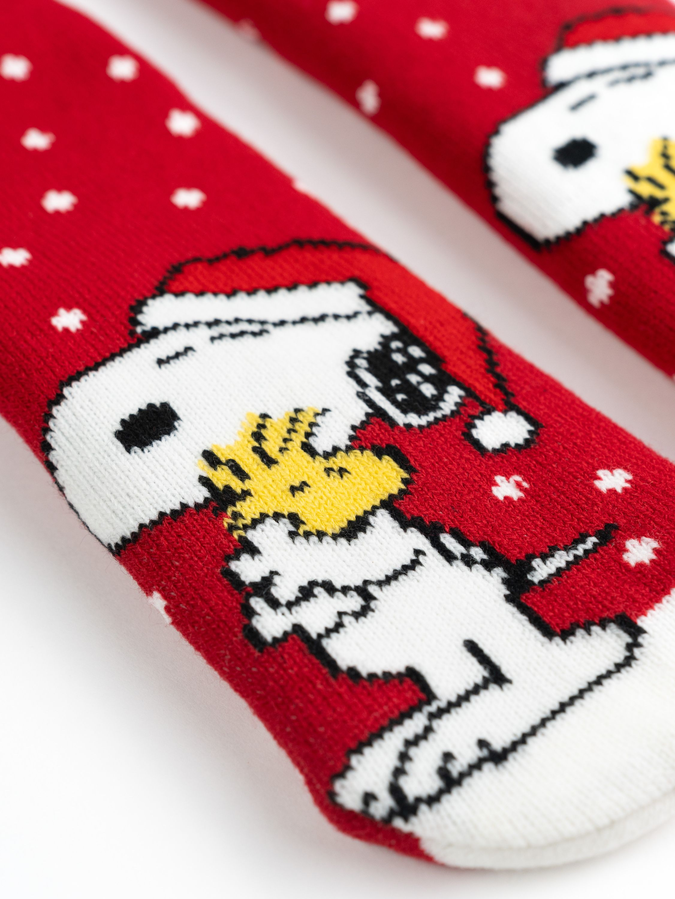 Zwei rote Weihnachtssocken mit Snoopy-Design, Snoopy mit Weihnachtsmütze.