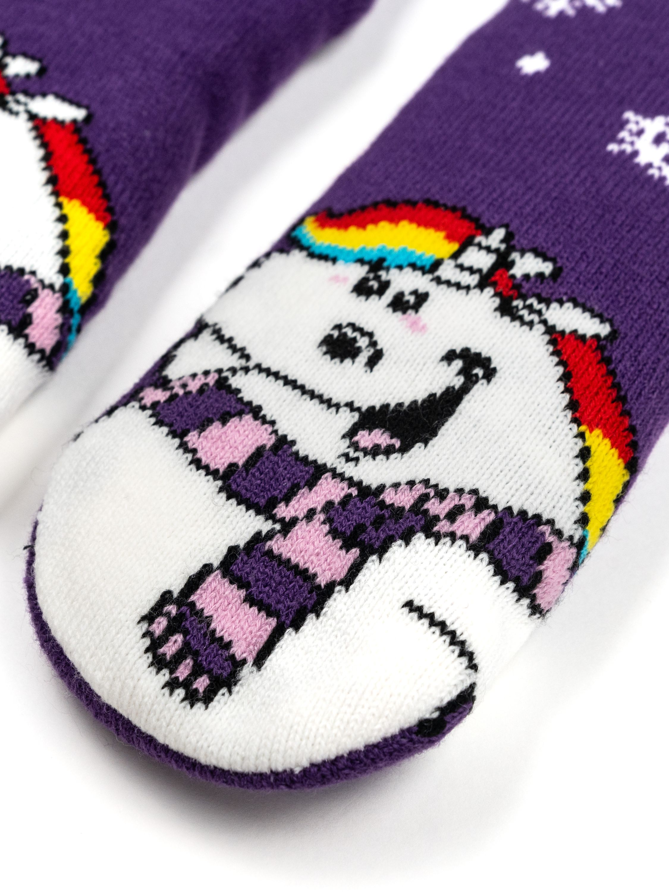 Lila Socken mit Einhorn-Gesicht und Schneeflocken. Das Einhorn hat eine Regenbogenmähne und einen Schal.