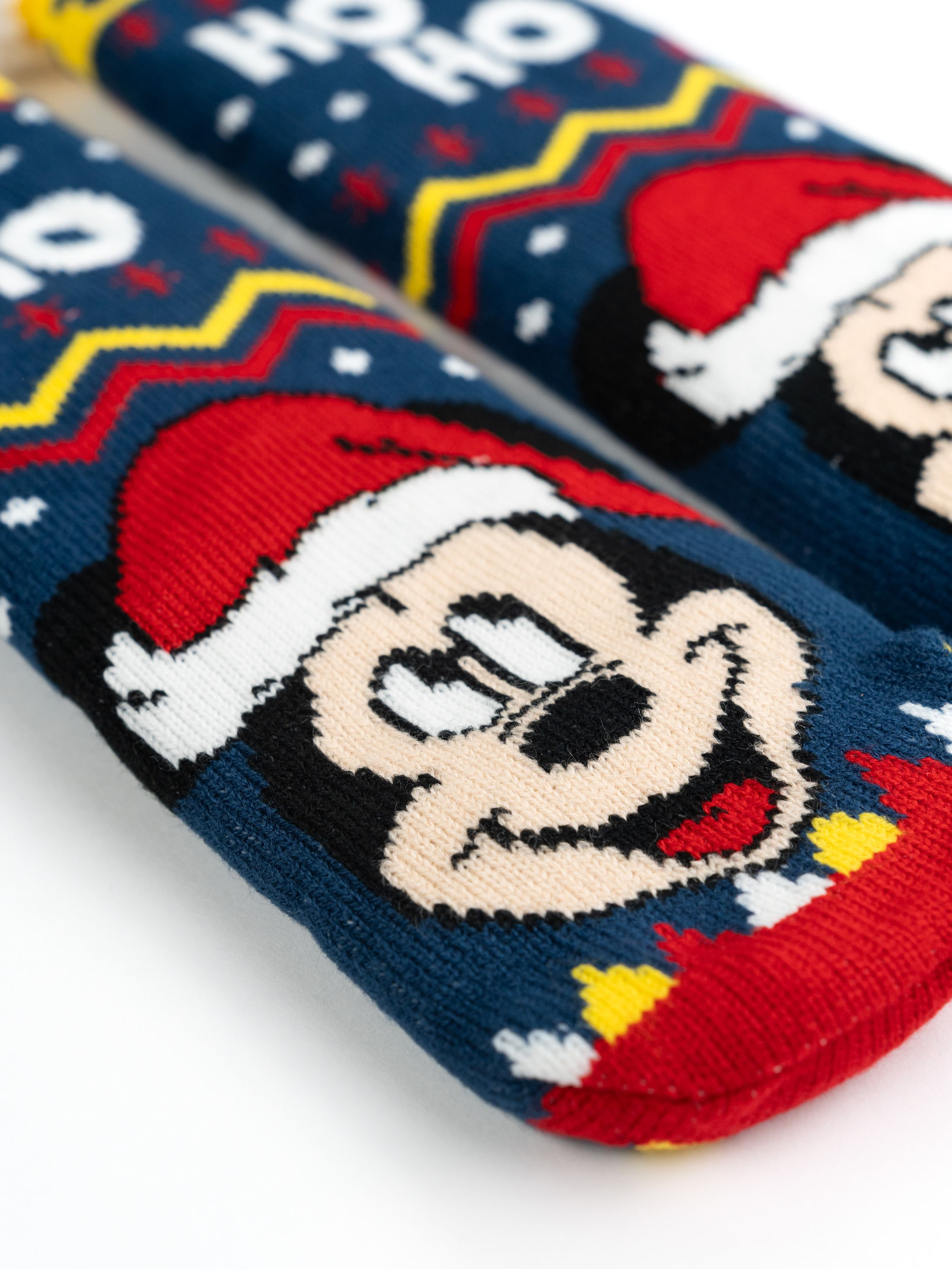 Nahaufnahme von zwei Weihnachtssocken mit Mickey Mouse mit Weihnachtsmütze, mit blauem und rotem Muster.