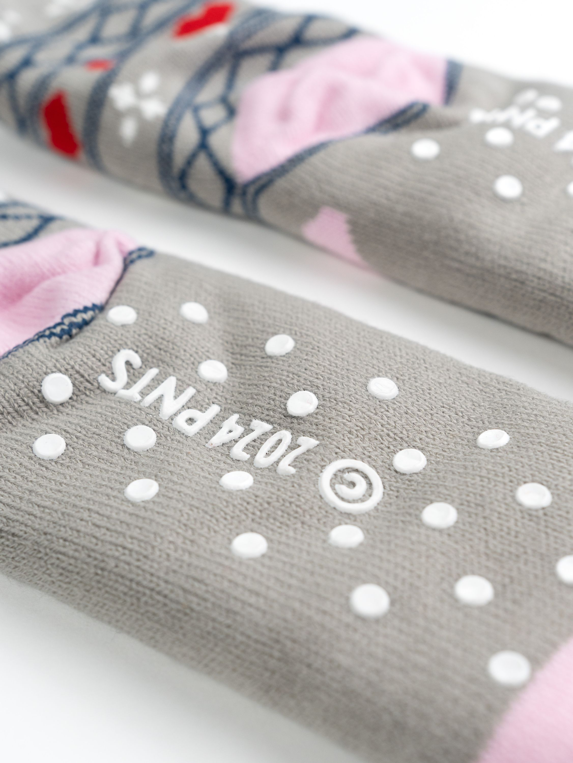 Paar Socken mit grauen, rosa und weißen Mustern. Punkte und '2024 PNTs'.