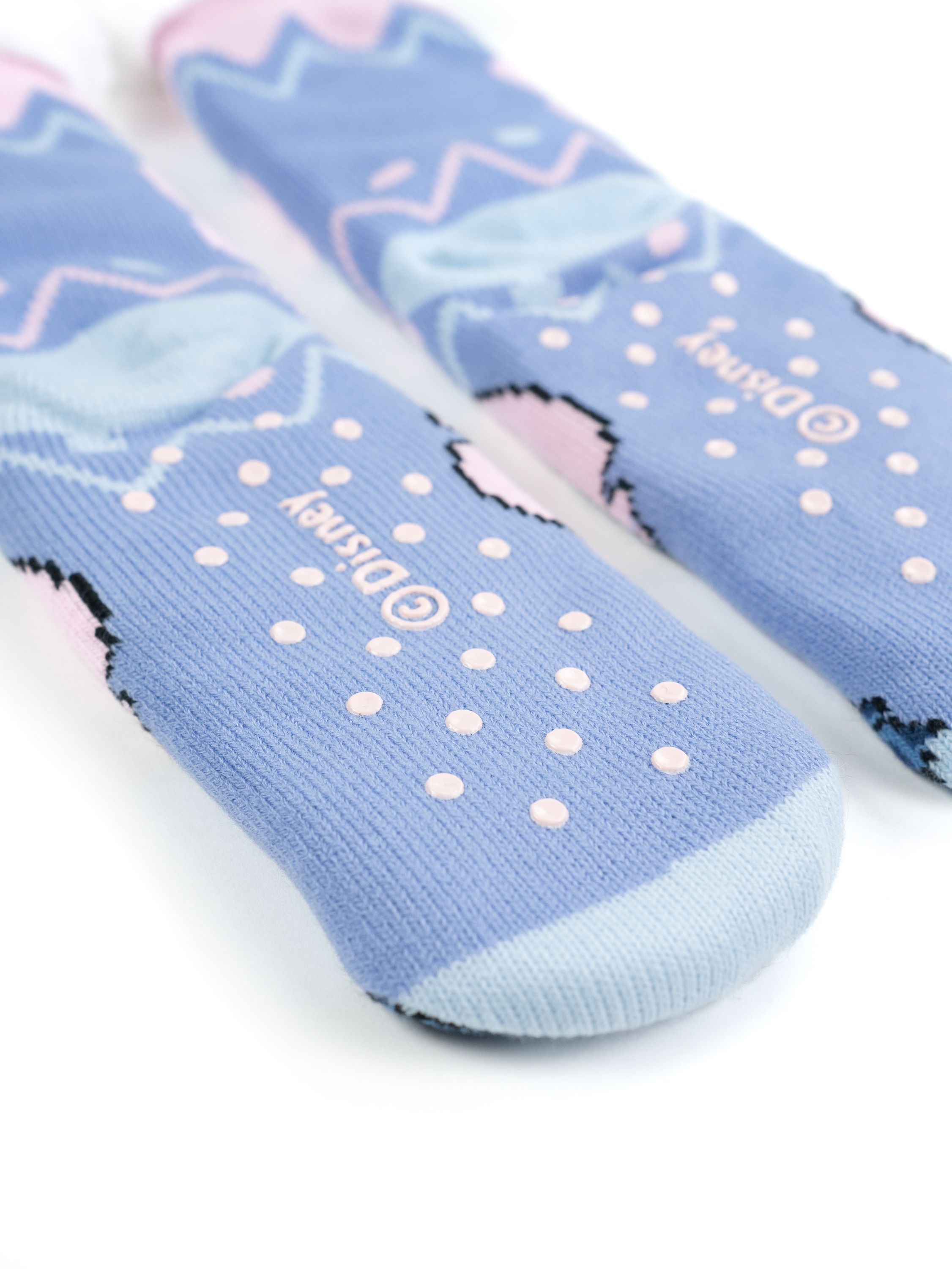 Paar hellblaue Socken mit rosa Punkten und Disney-Logo. Weißer Hintergrund.