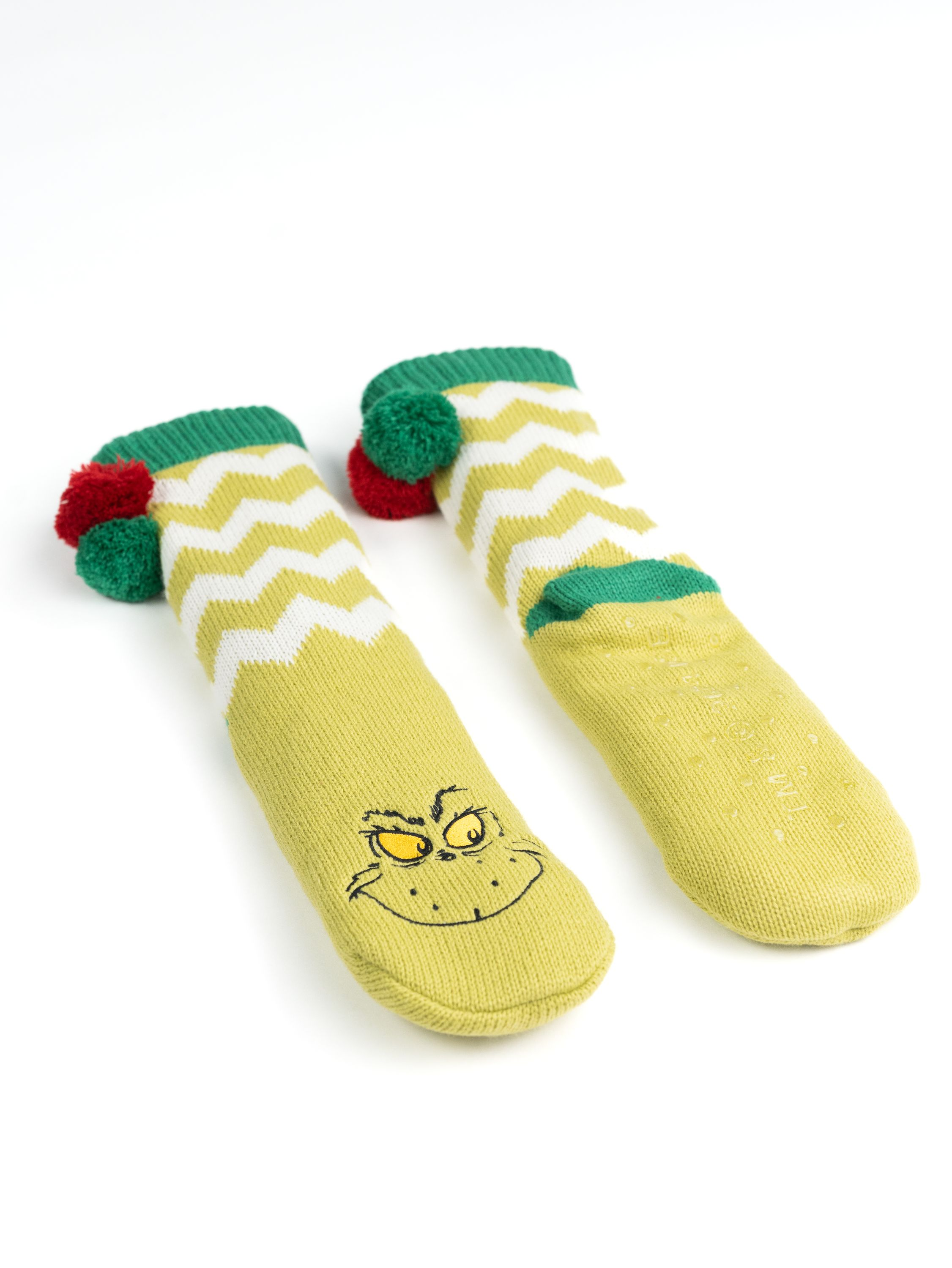 Paar Grinch-Socken. Limettengrün mit weißen Chevron-Mustern. Grinch-Gesicht auf den Zehen und rote Bommel.