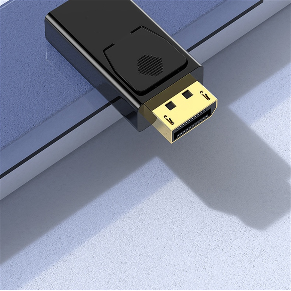 Ein schwarzer Displayport-Adapter mit einem goldfarbenen Anschluss. Er liegt auf einer blauen Oberfläche.
