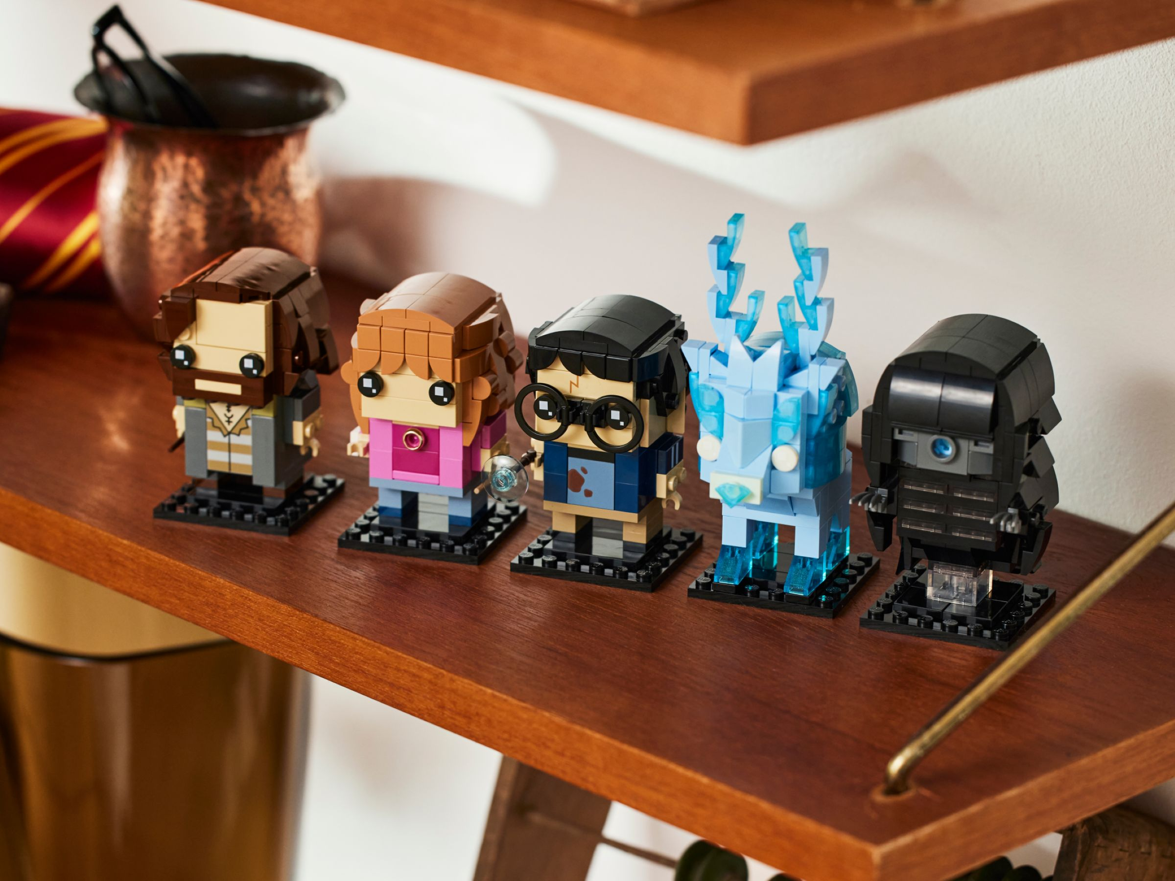 LEGO BrickHeadz Figuren von Charakteren auf einem Holzregal, darunter Harry Potter und Hermine.