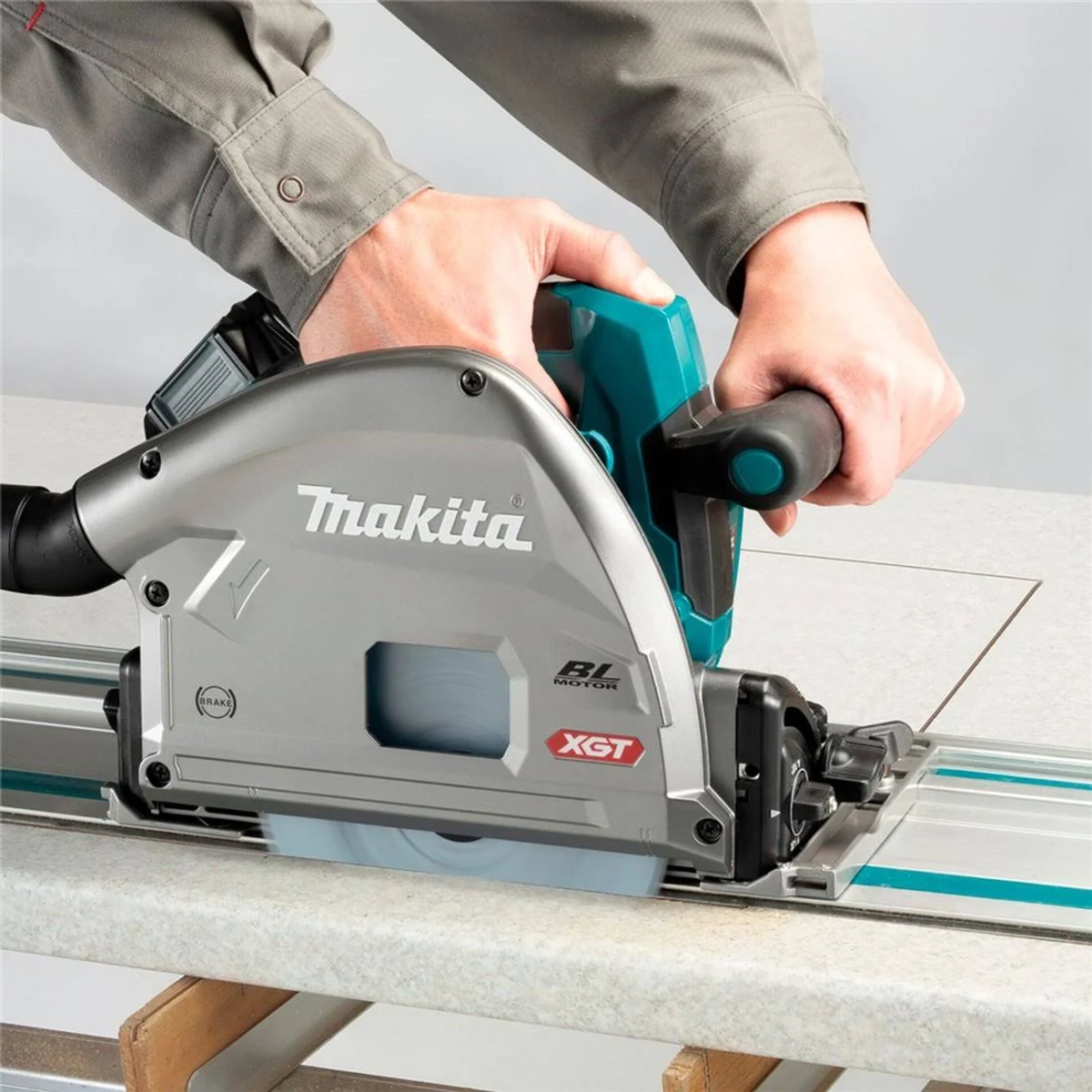 Eine Makita Kreissäge schneidet eine weiße Oberfläche. Eine Person hält die Säge.