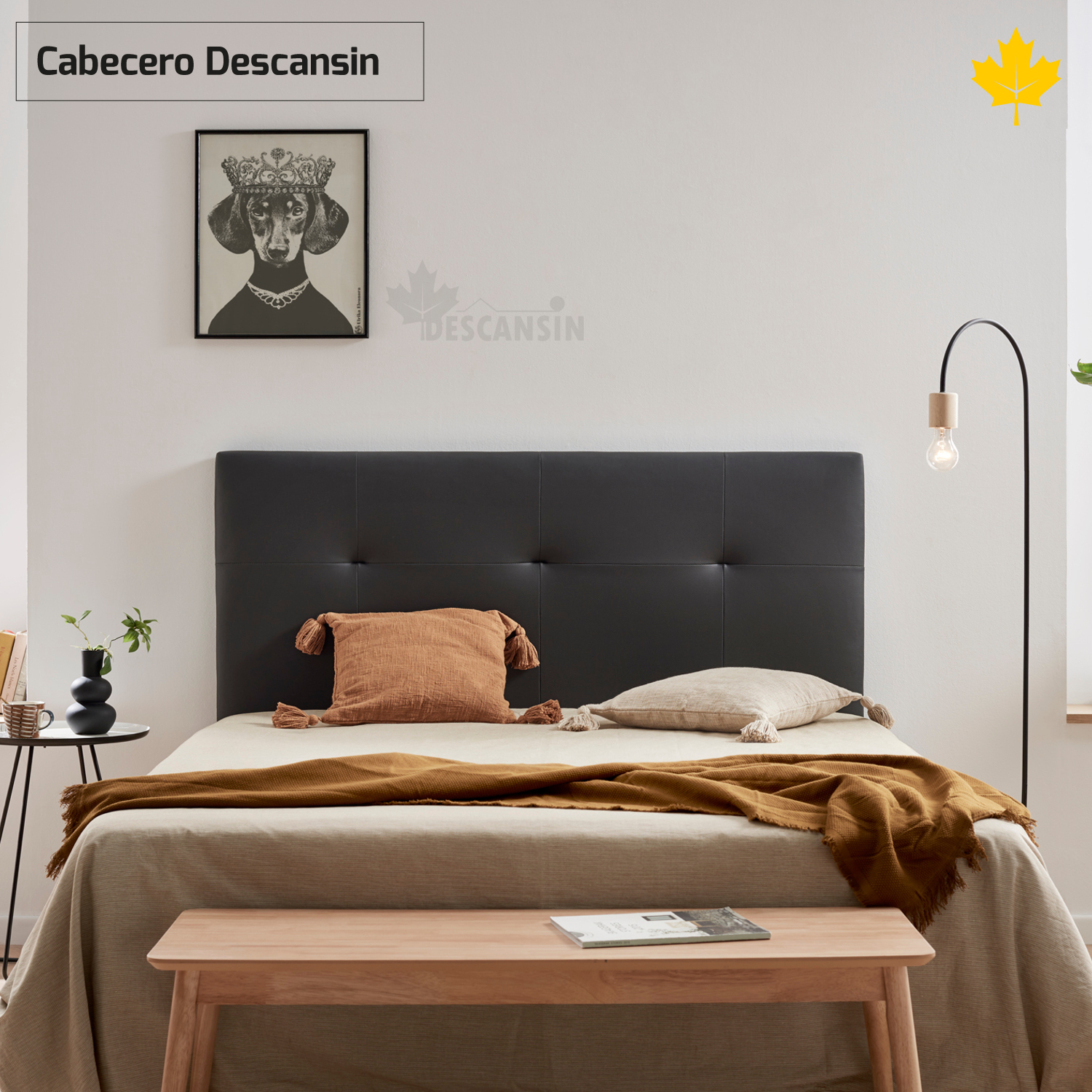 Una escena de dormitorio con una cama, un banco y una lámpara. Hay arte en la pared. La cama tiene una manta.