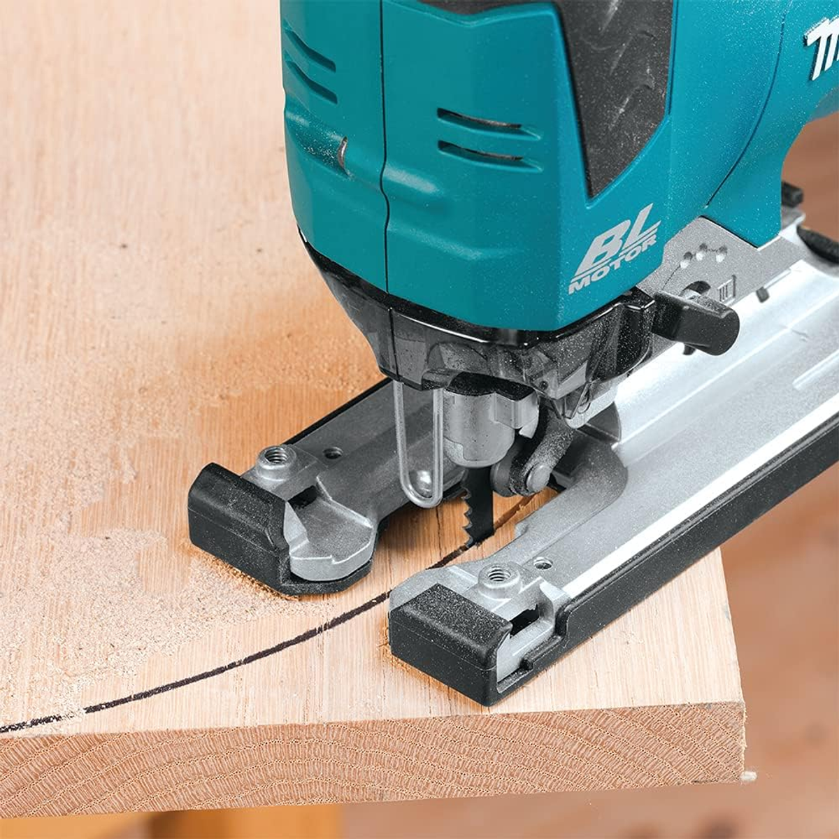 Un primo piano di un seghetto alternativo Makita verde acqua che taglia una linea su una tavola di legno.