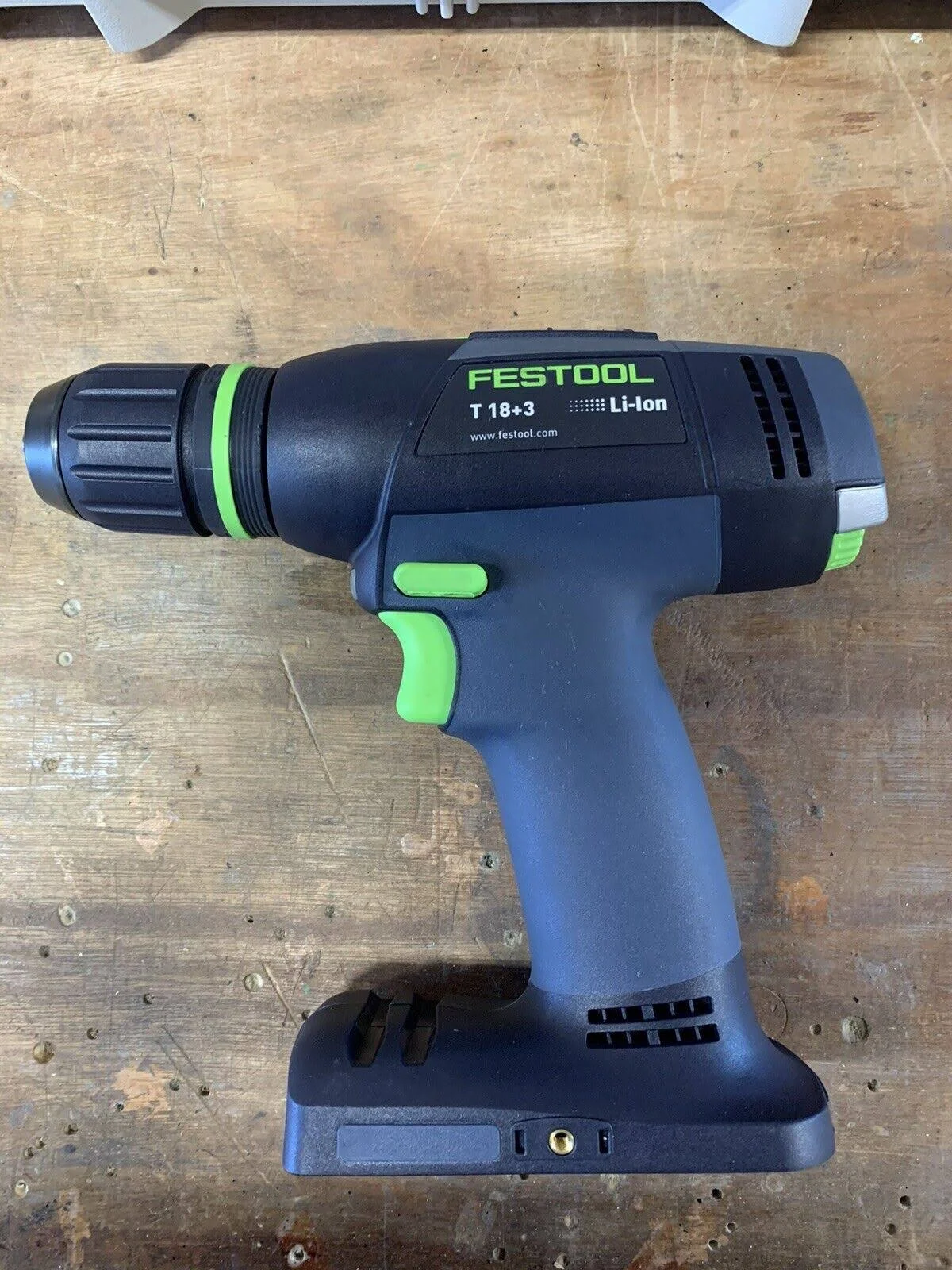 Czarno-niebieska wiertarka akumulatorowa na drewnianej powierzchni. Zielone akcenty na wiertarce.