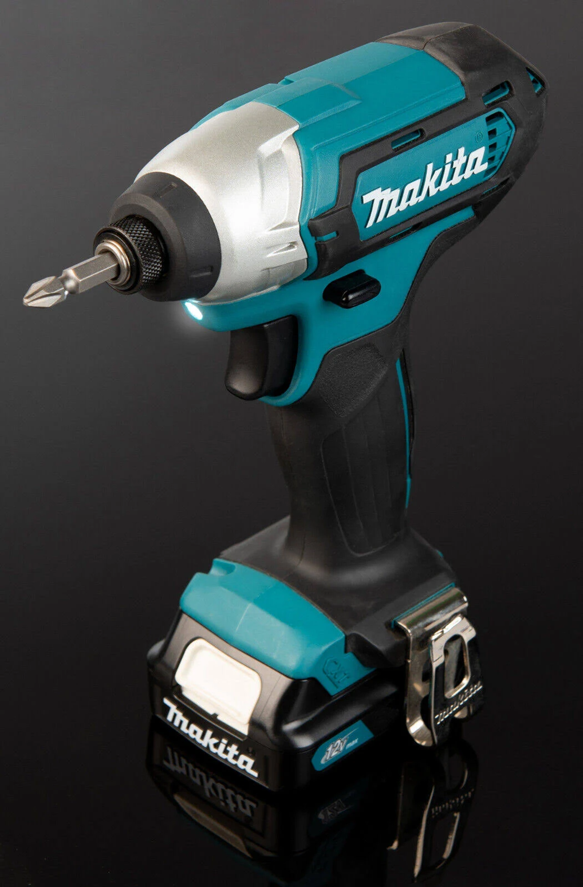 Un avvitatore a impulsi Makita verde acqua e nero con batteria e punta, su una superficie scura e riflettente.