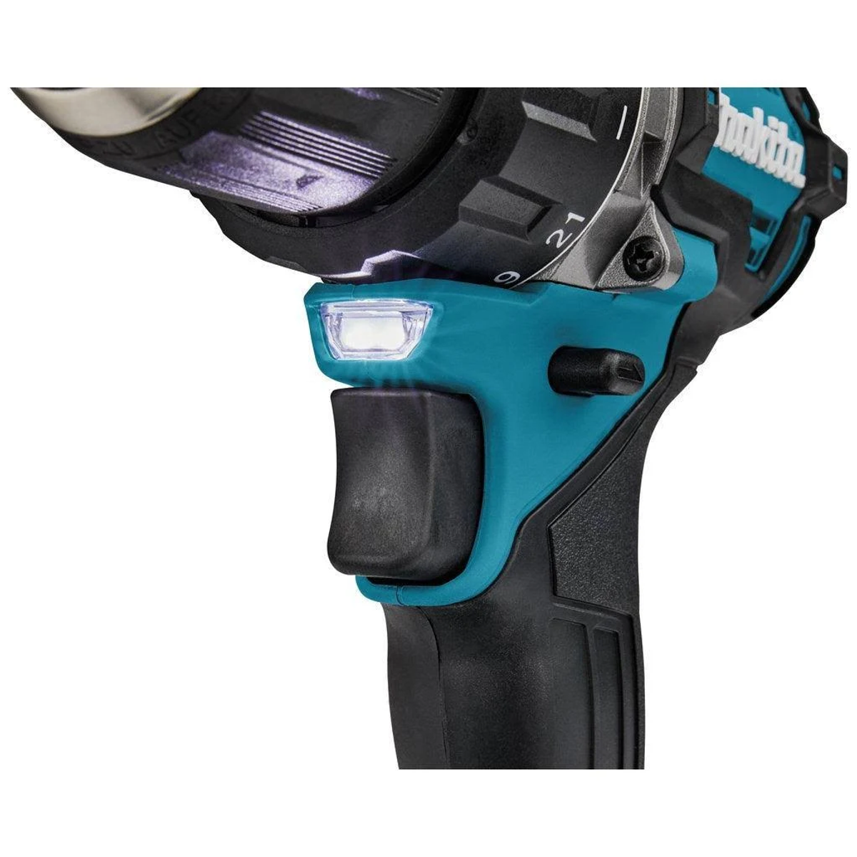 Primer plano de un taladro Makita azul verdoso y negro. La luz está encendida, mostrando un botón de encendido. El fondo está desenfocado.