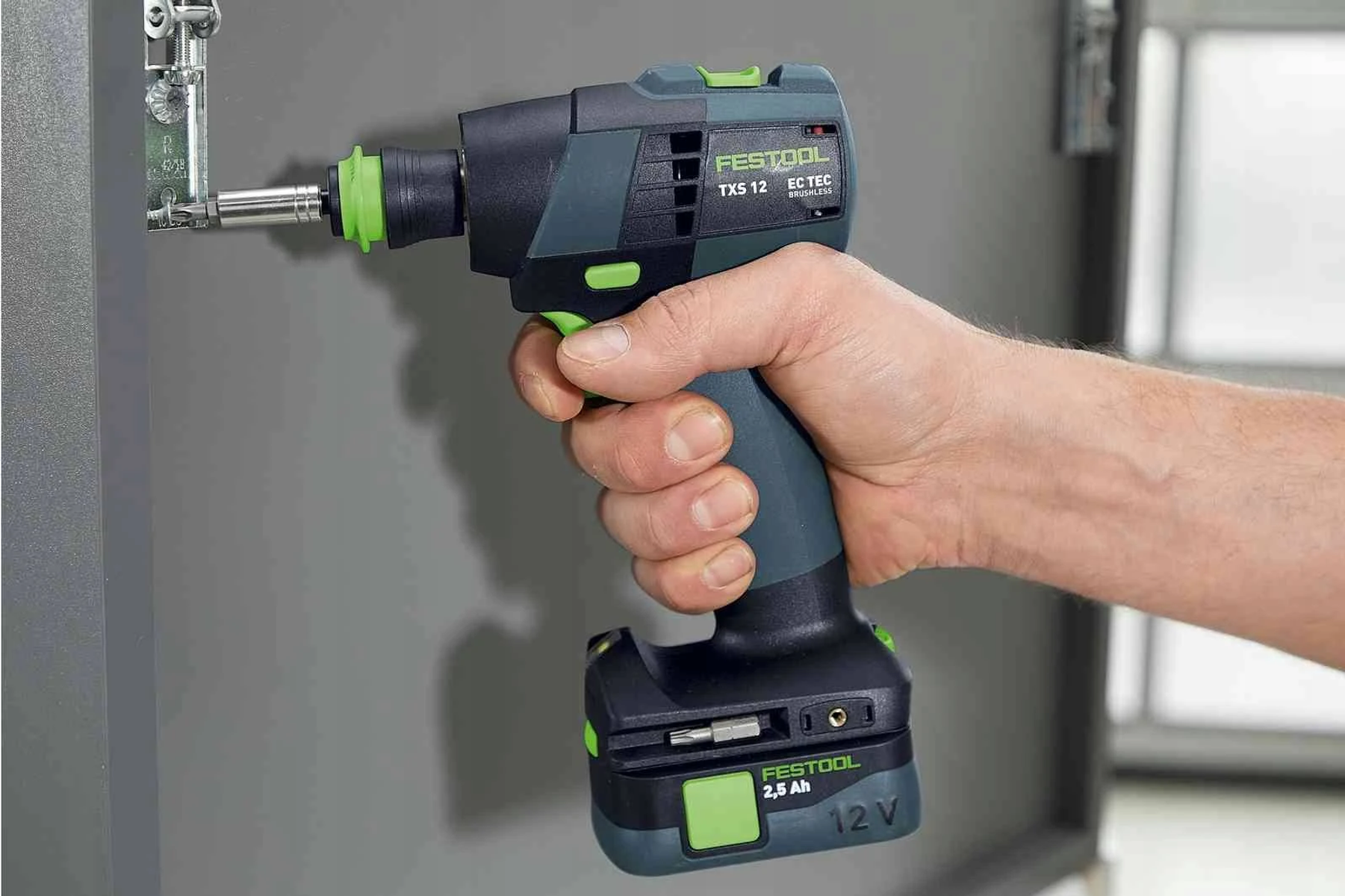 Una persona sostiene un taladro inalámbrico Festool, taladrando una bisagra.