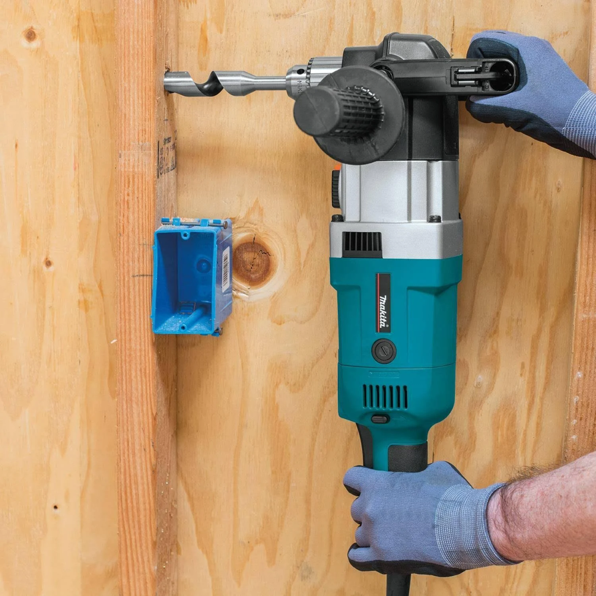 Un trabajador taladrando un agujero con un taladro Makita en una pared de madera.