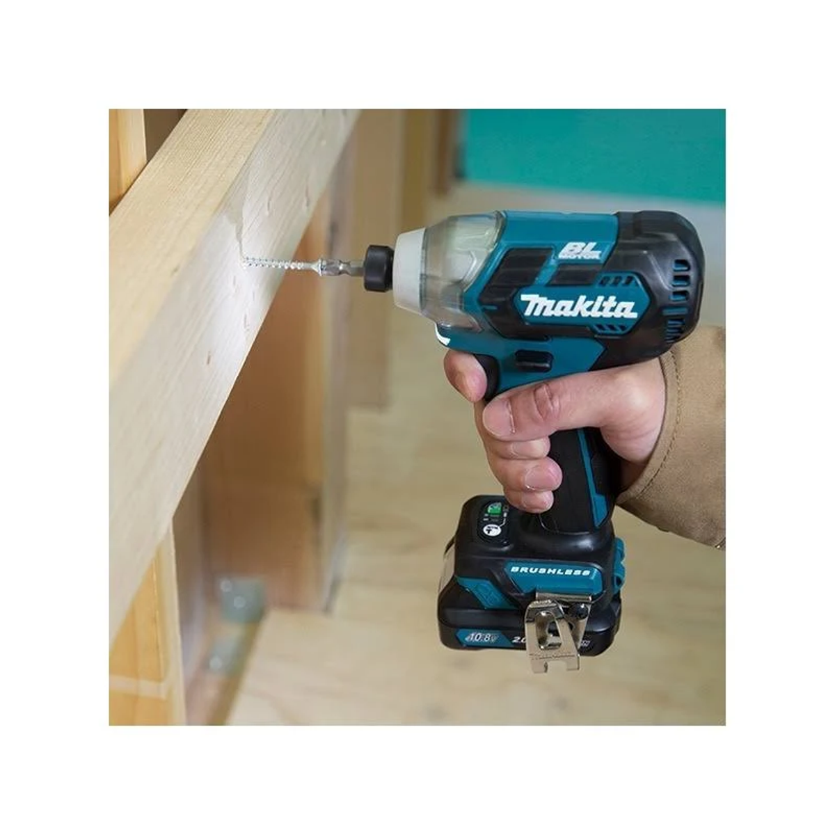 Una persona usando un atornillador de impacto Makita turquesa para atornillar en una viga de madera.