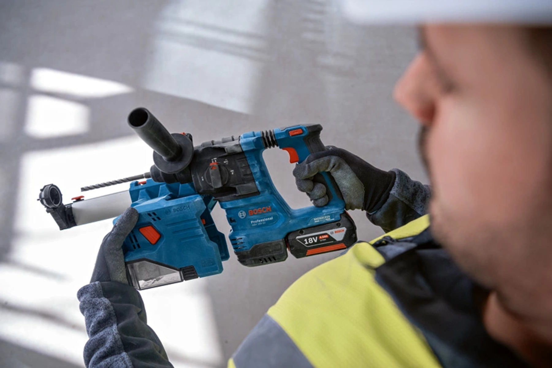 Un hombre sosteniendo un martillo perforador Bosch azul y negro, trabajando en una pared.