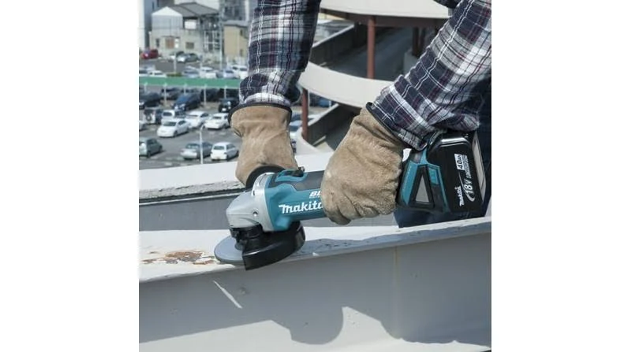 Un trabajador usa una amoladora Makita en una viga de acero, usando guantes de trabajo.