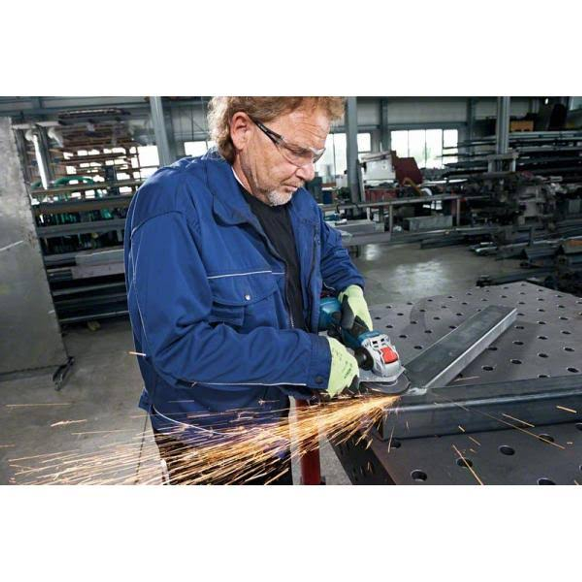 Una persona, con gafas de seguridad, usa una amoladora angular Makita sobre metal, saltan chispas.