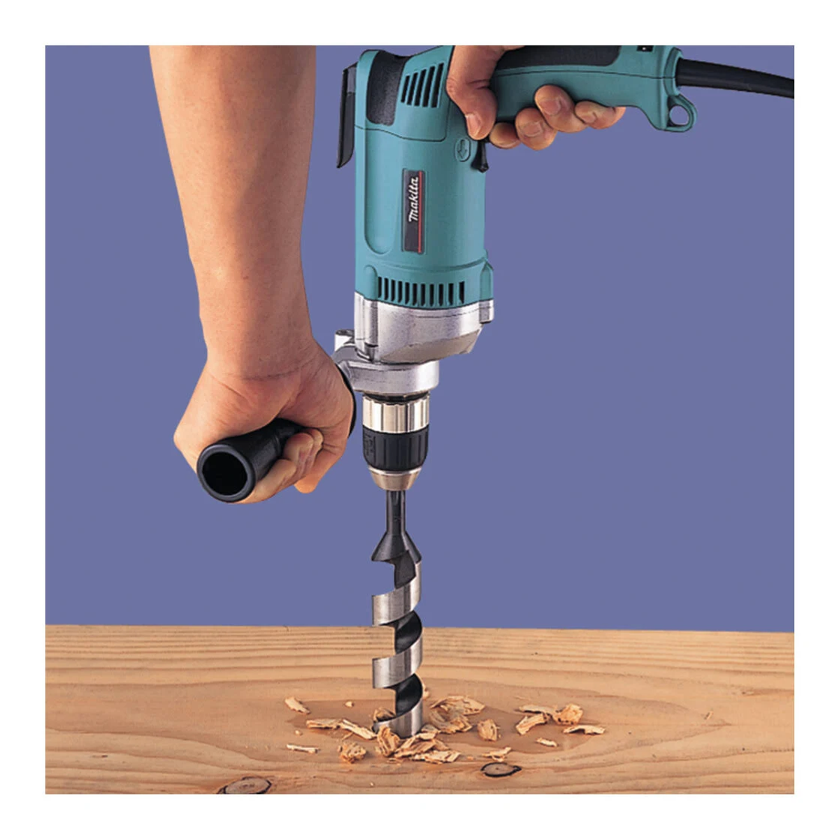 Una mano taladra madera con un taladro azul Makita. Se ven virutas de madera.
