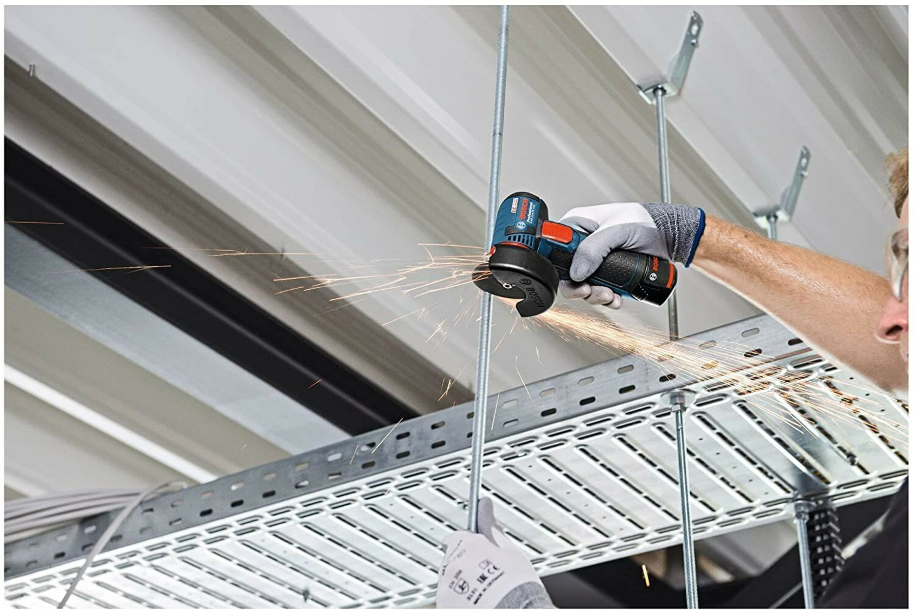 Osoba używająca szlifierki kątowej, iskry, na metalowej konstrukcji.