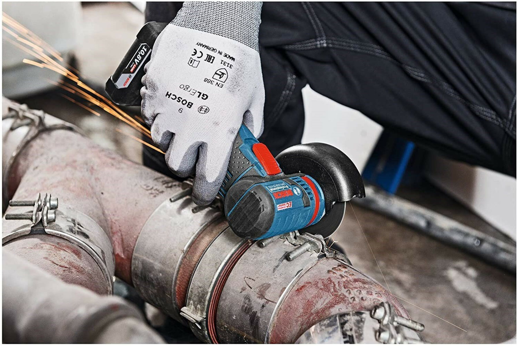 Osoba szlifująca metalową rurę. Iskry lecą. Niebiesko-czerwona szlifierka. Białe rękawice.