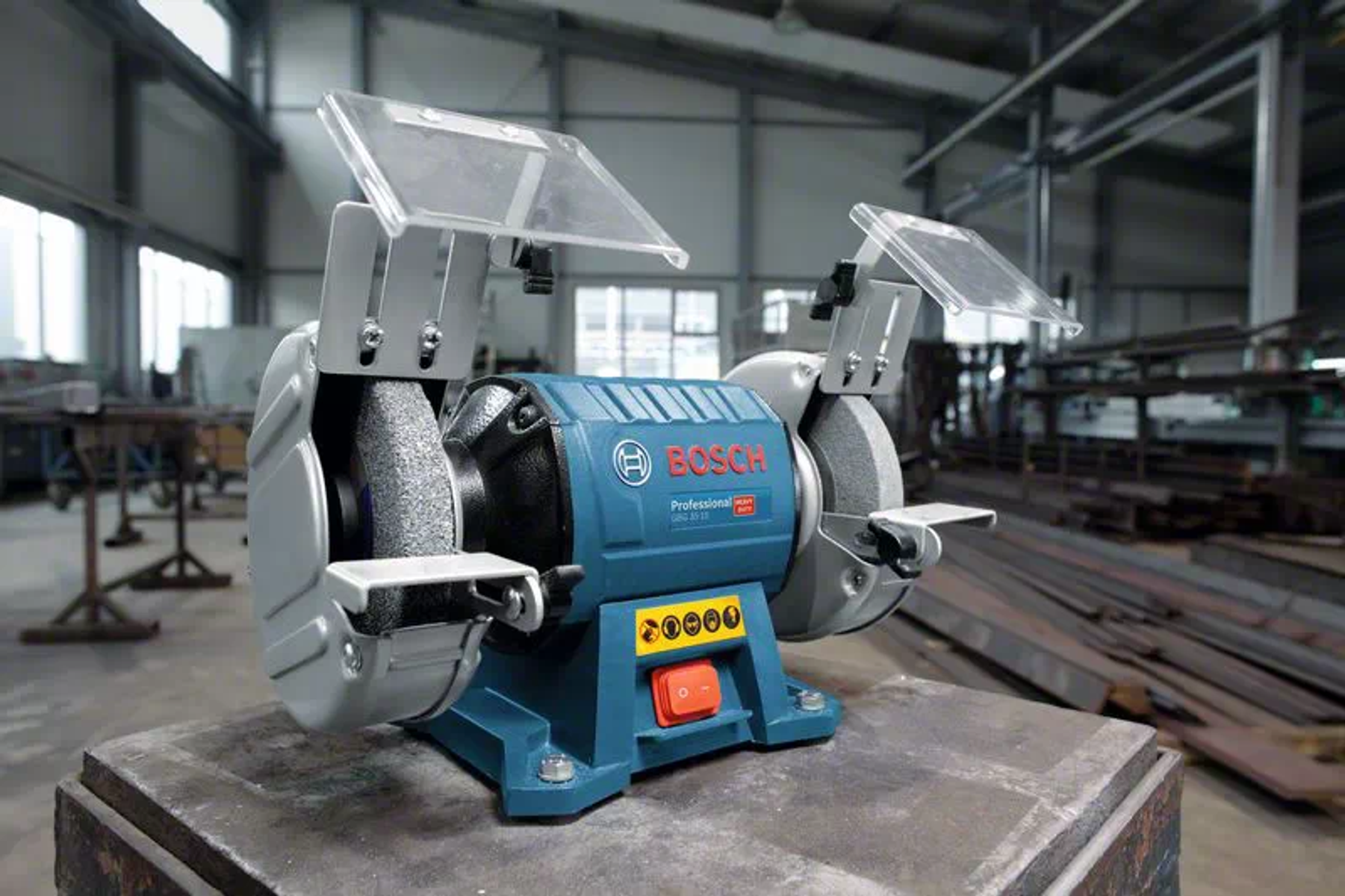 Bir atölyede metal bir masa üzerinde mavi Bosch tezgah taşlama makinesi.