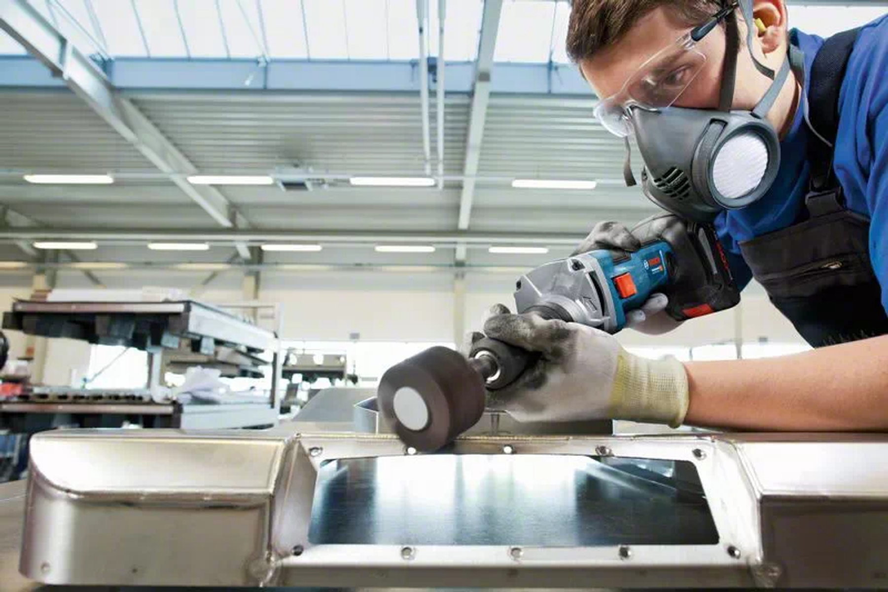 Mężczyzna w warsztacie używający szlifierki na metalowej powierzchni.