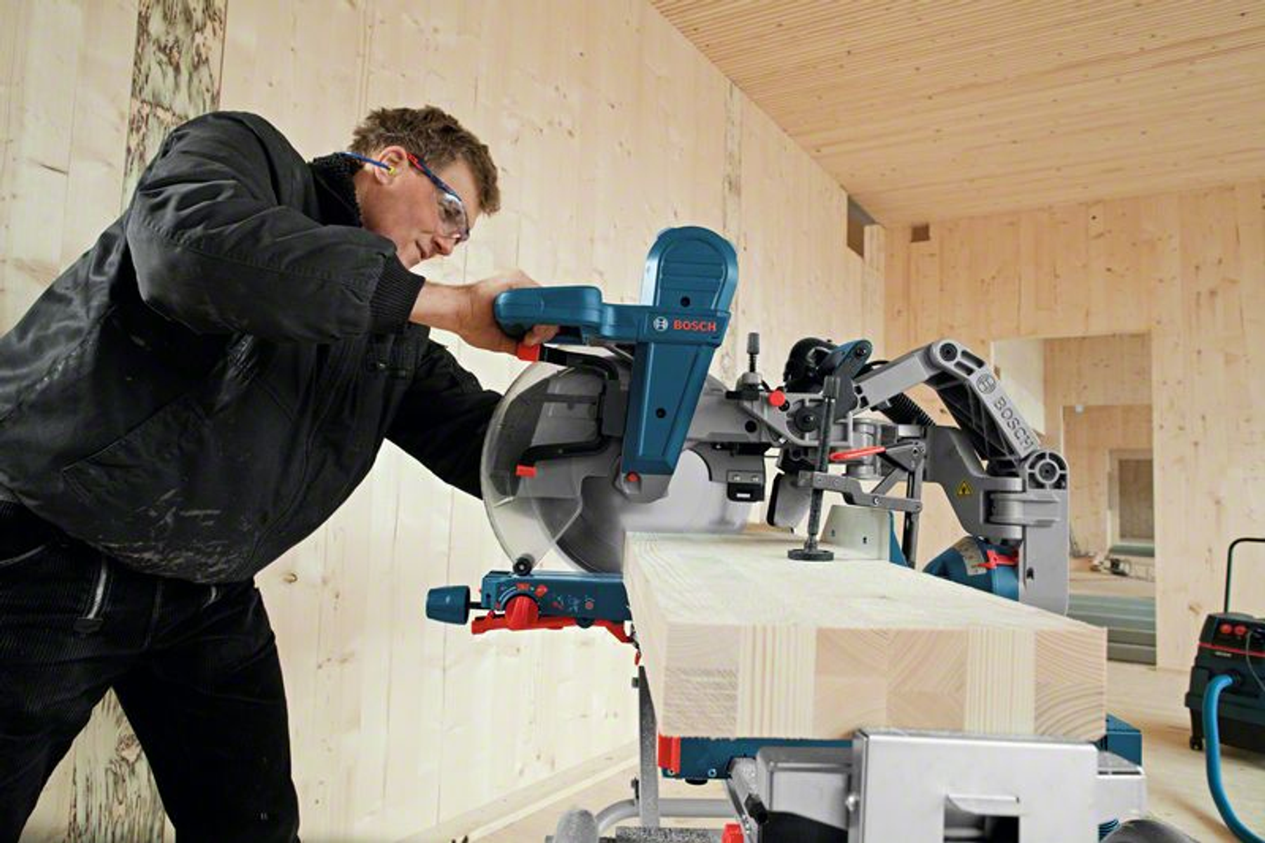 Ein Mann bedient eine Bosch-Gehrungsäge und schneidet Holz.