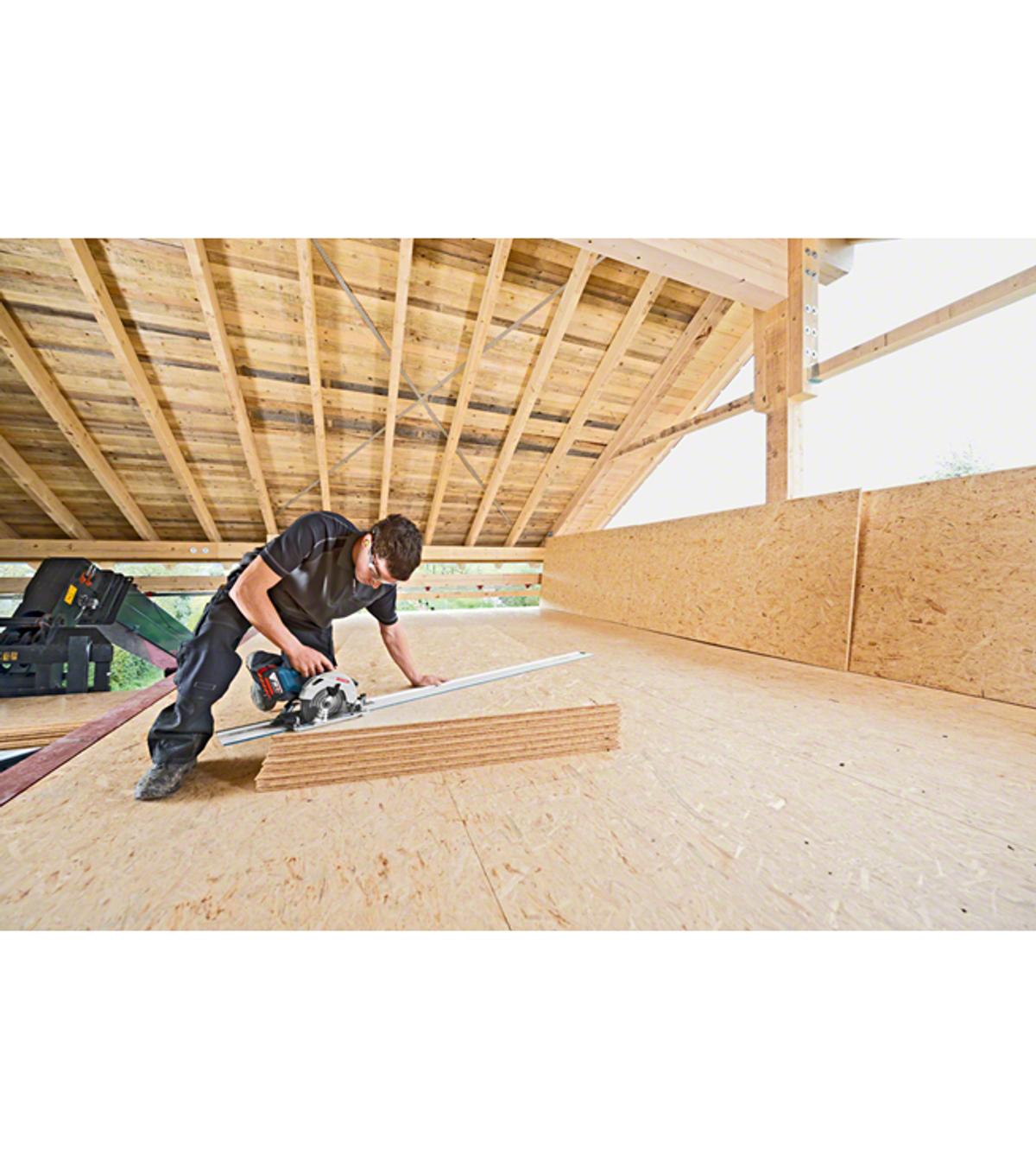 Mężczyzna tnący drewno piłą tarczową na budowie. Panele drewniane są cięte.