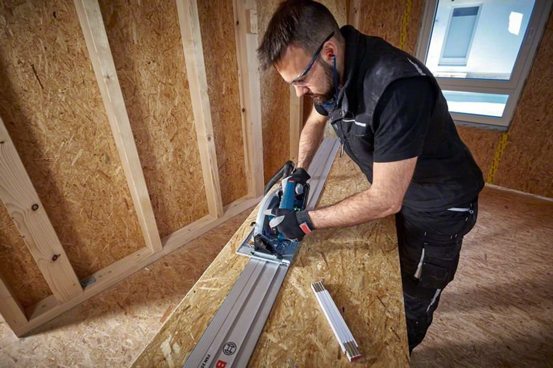 Un hombre usando una sierra circular para cortar madera en un sitio de construcción.