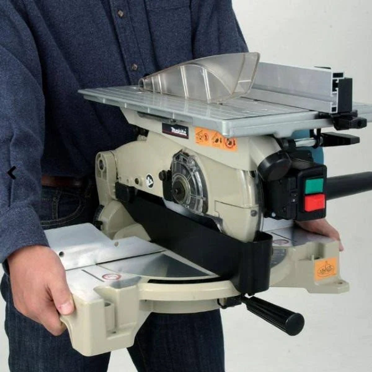 Ein Mann hält eine Makita Tischkreissäge. Er trägt ein blaues Hemd. Säge ist beige und grau.