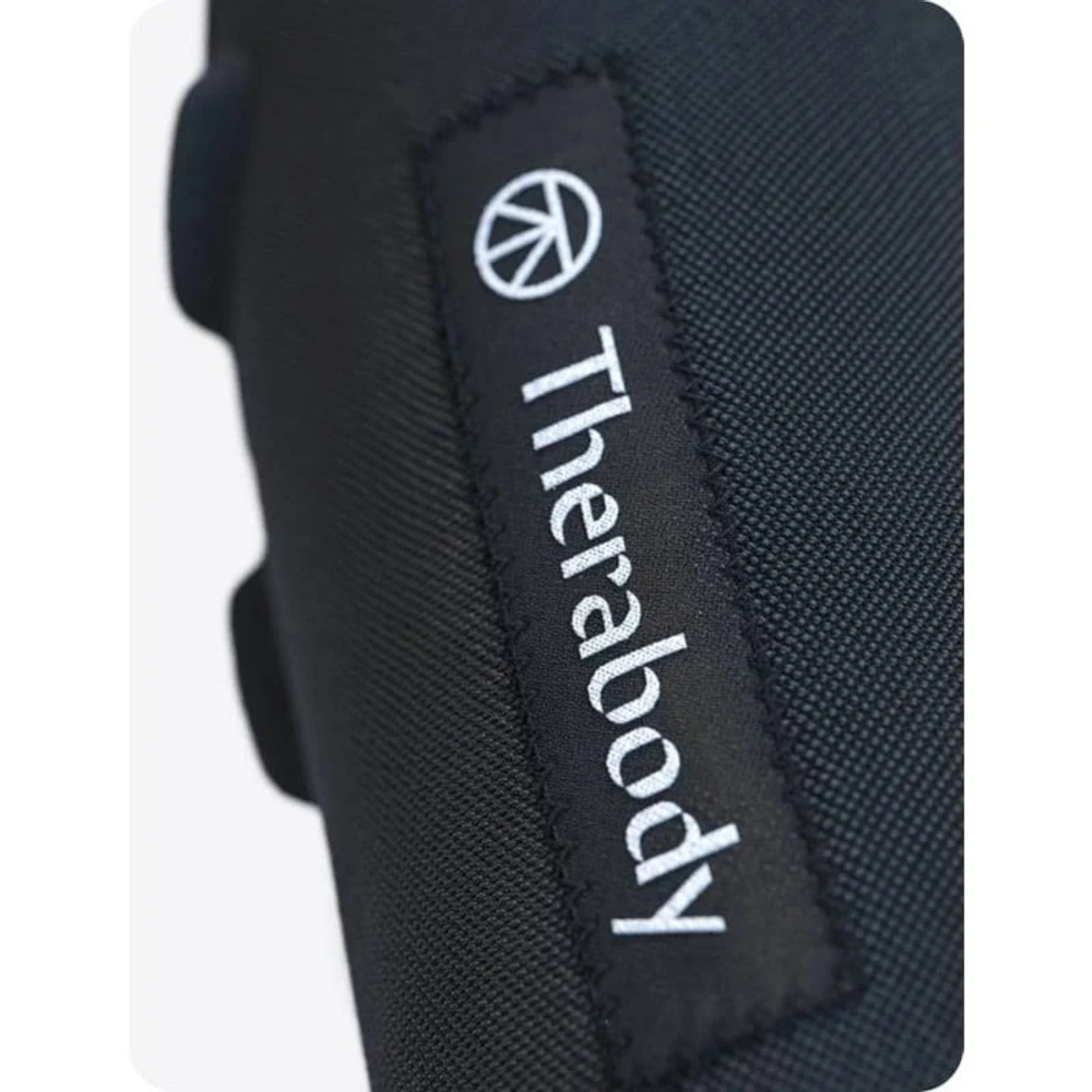 Superficie negra, texturizada con el logo blanco 'Therabody'.