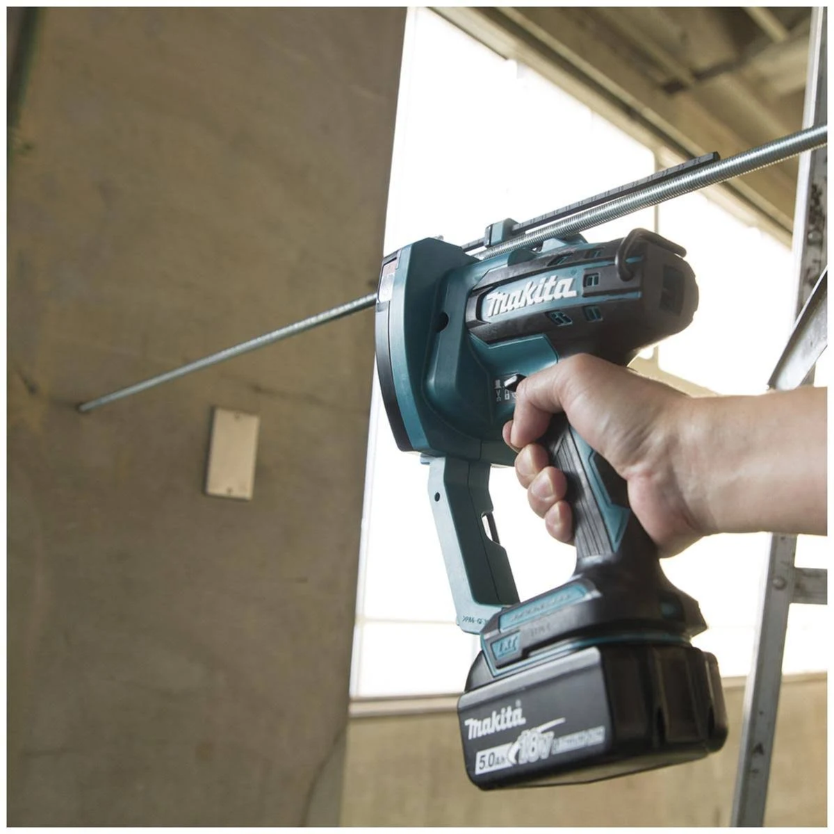 Hand hält Makita-Elektrowerkzeug, befestigt Stange in Betonwand.