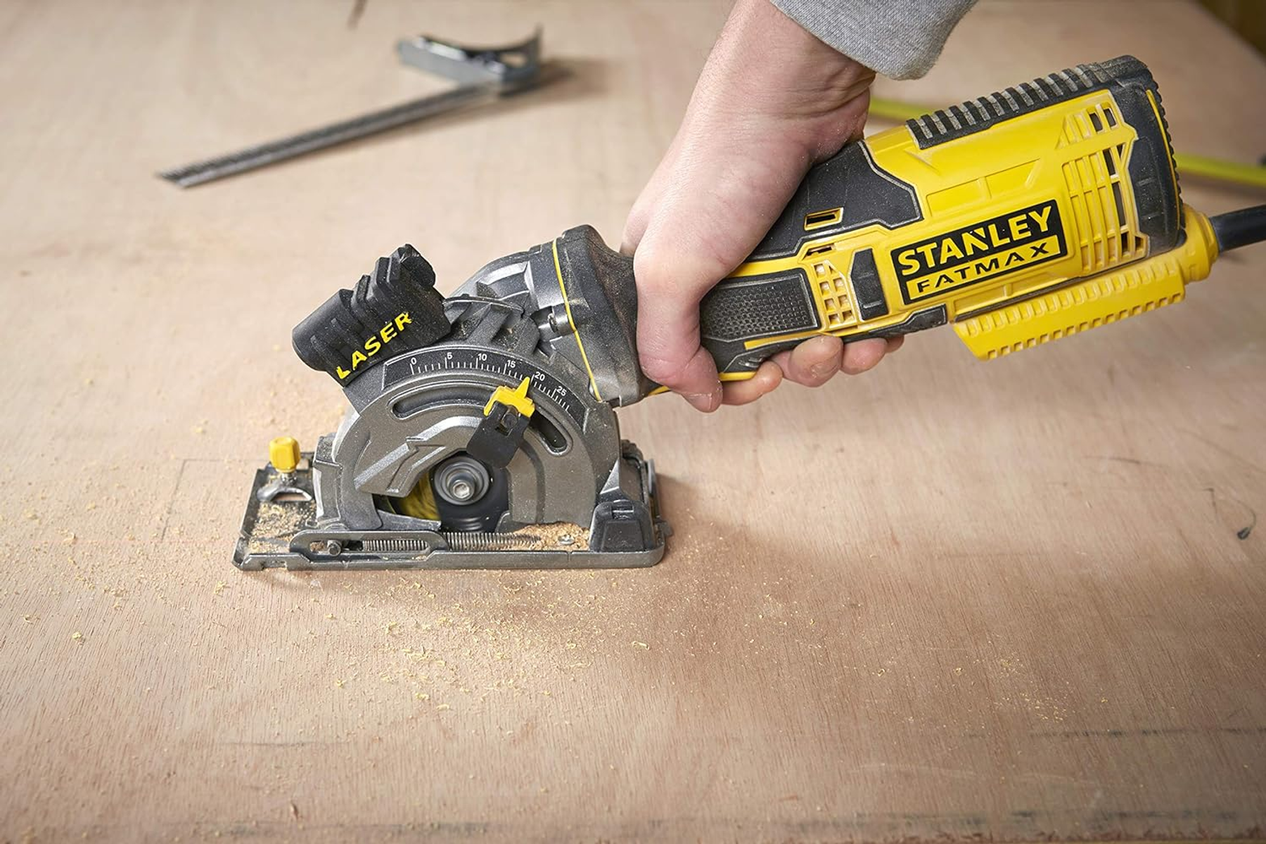 Eine Person, die eine gelbe Kreissäge auf Holz verwendet. Die Säge hat eine Laserführung.