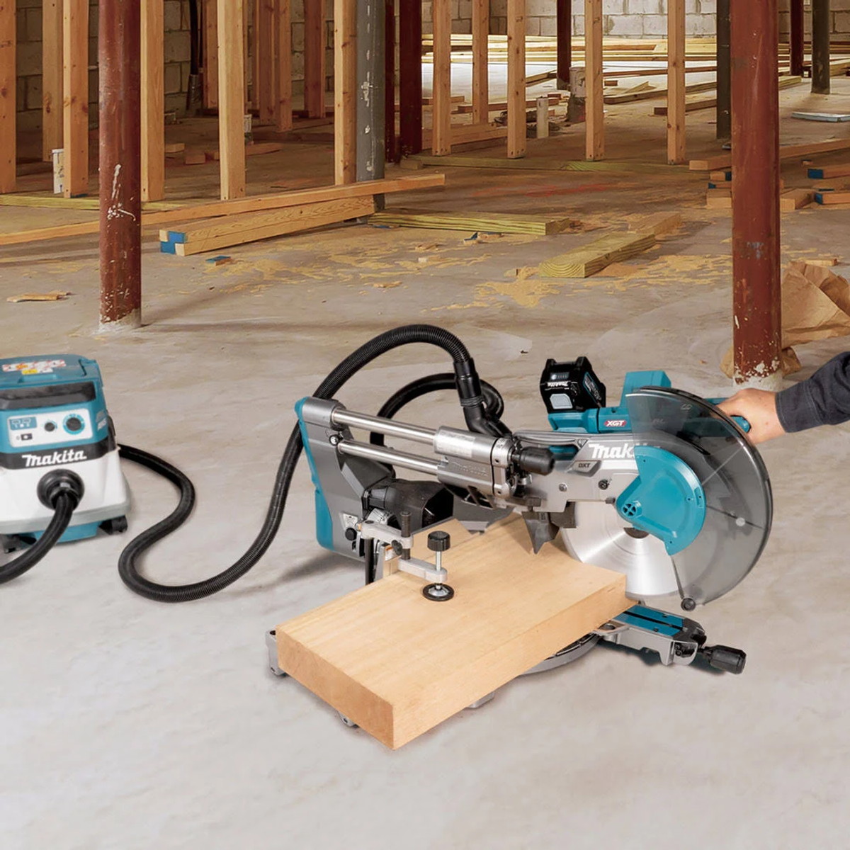 Holz mit einer Makita Säge sägen. Die Säge steht auf einem Holzbrett. Baustellenhintergrund.