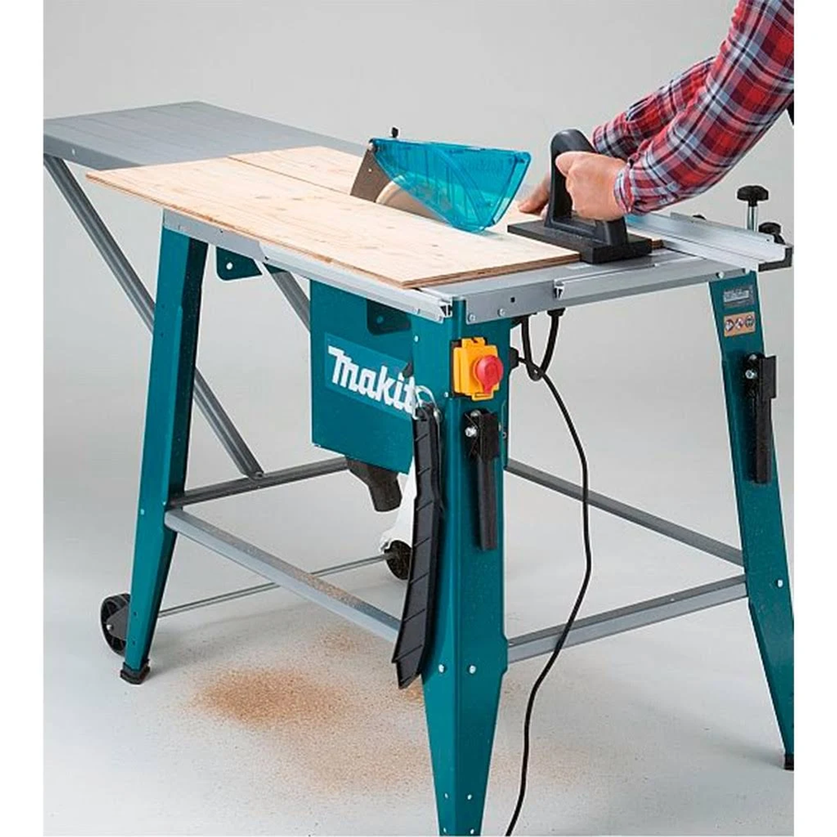 Eine Makita-Tischkreissäge. Eine Person schneidet damit Holz. Es ist türkis und grau.