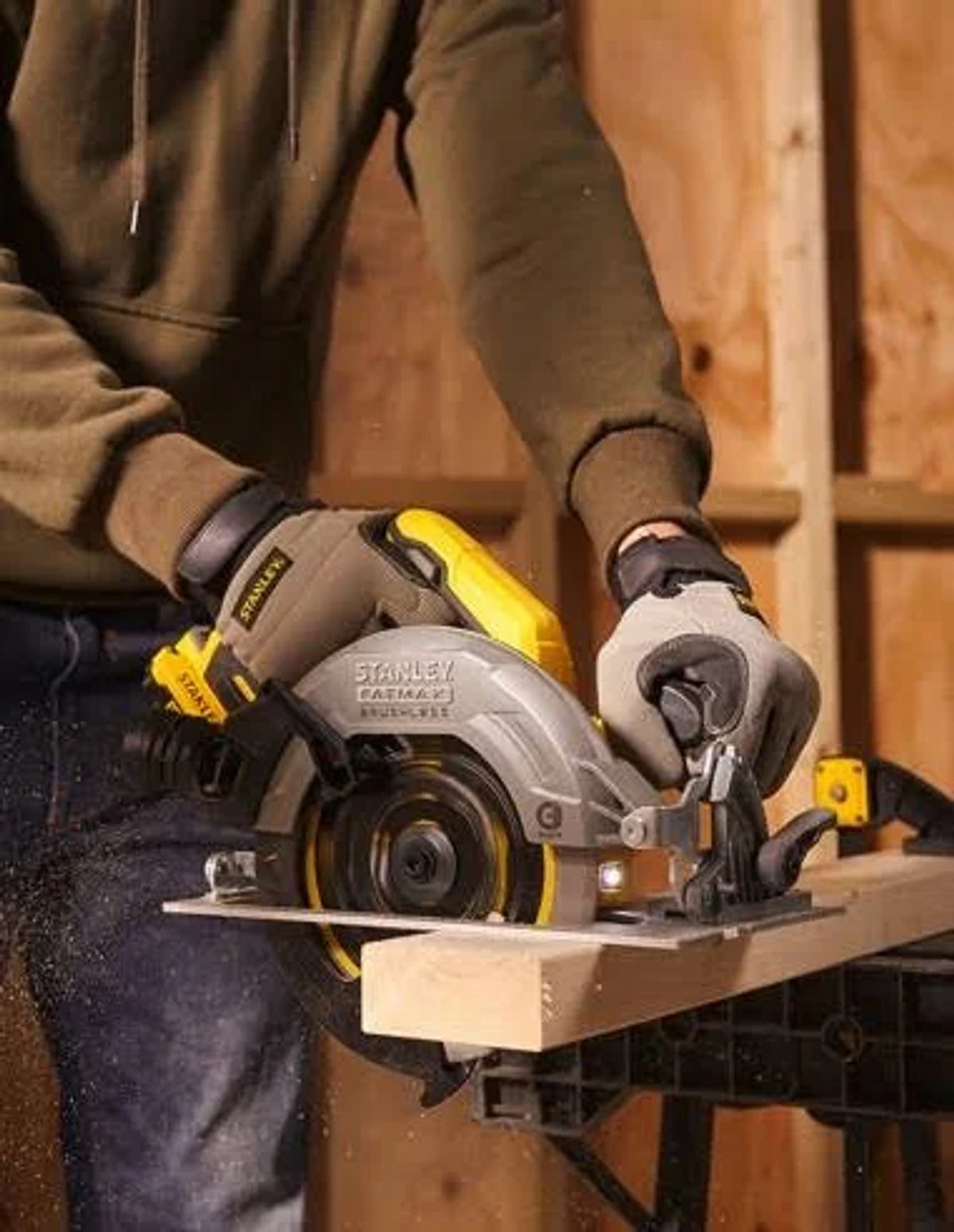 Eine Person mit Handschuhen schneidet mit einer Kreissäge ein Holzstück auf einer Holzoberfläche.