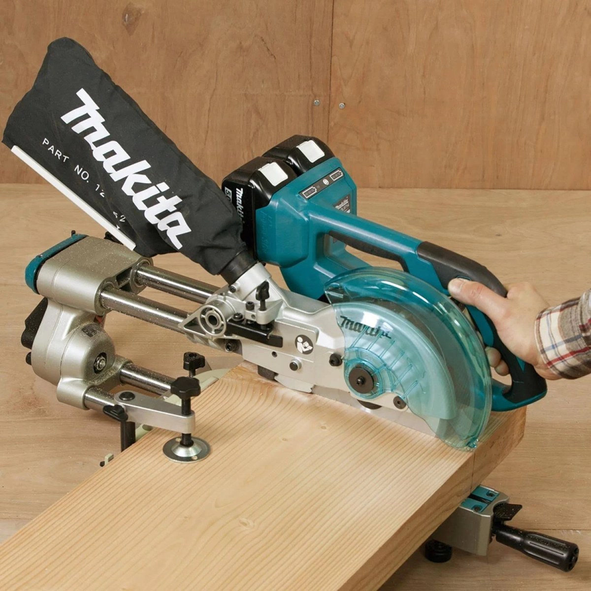 Mann schneidet Holz mit Makita Kreissäge. Sägemehltasche und Holz sichtbar.