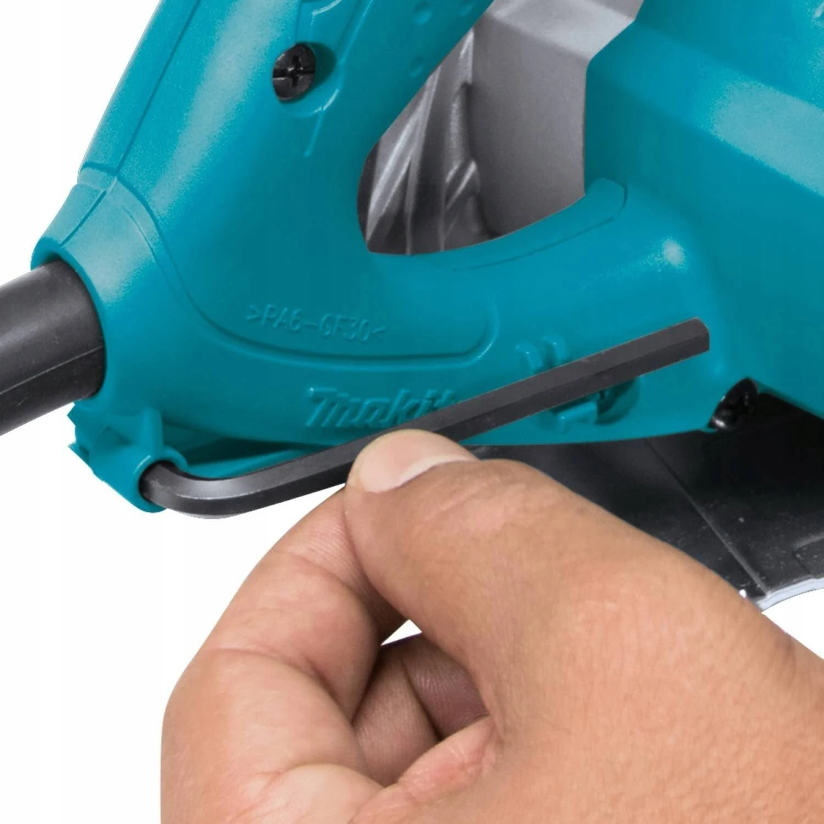Una mano sosteniendo una llave inglesa ajustando una sierra circular Makita turquesa.