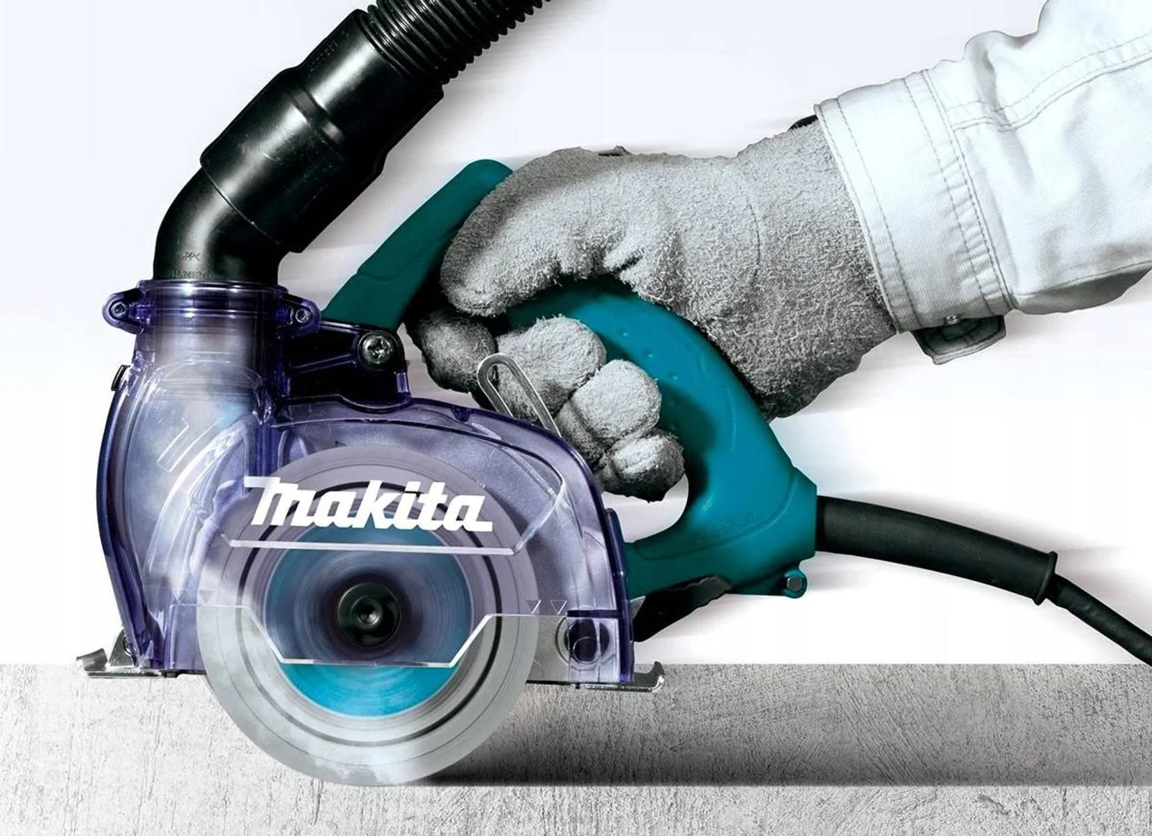 Una persona con un guante utiliza una cortadora de concreto Makita. La herramienta es turquesa y negra.