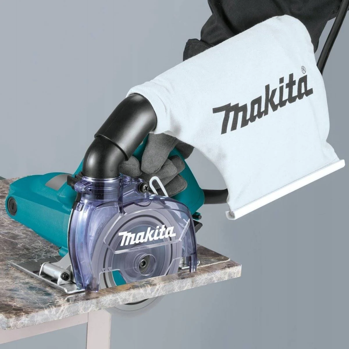 Una persona que usa una amoladora Makita. La amoladora tiene un protector transparente y una bolsa de polvo blanca.