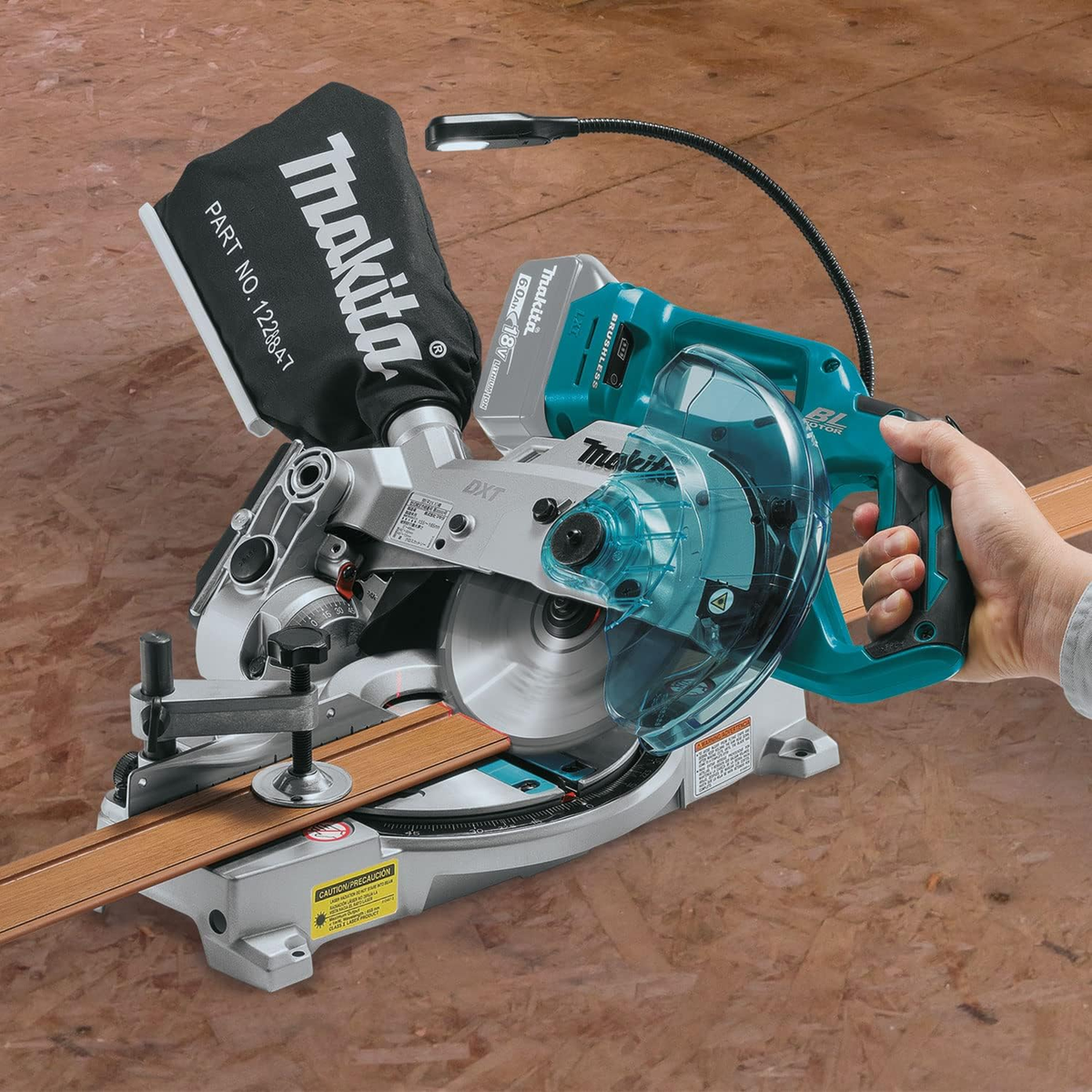 Una sierra ingletadora Makita con hoja circular, base de madera y una mano.