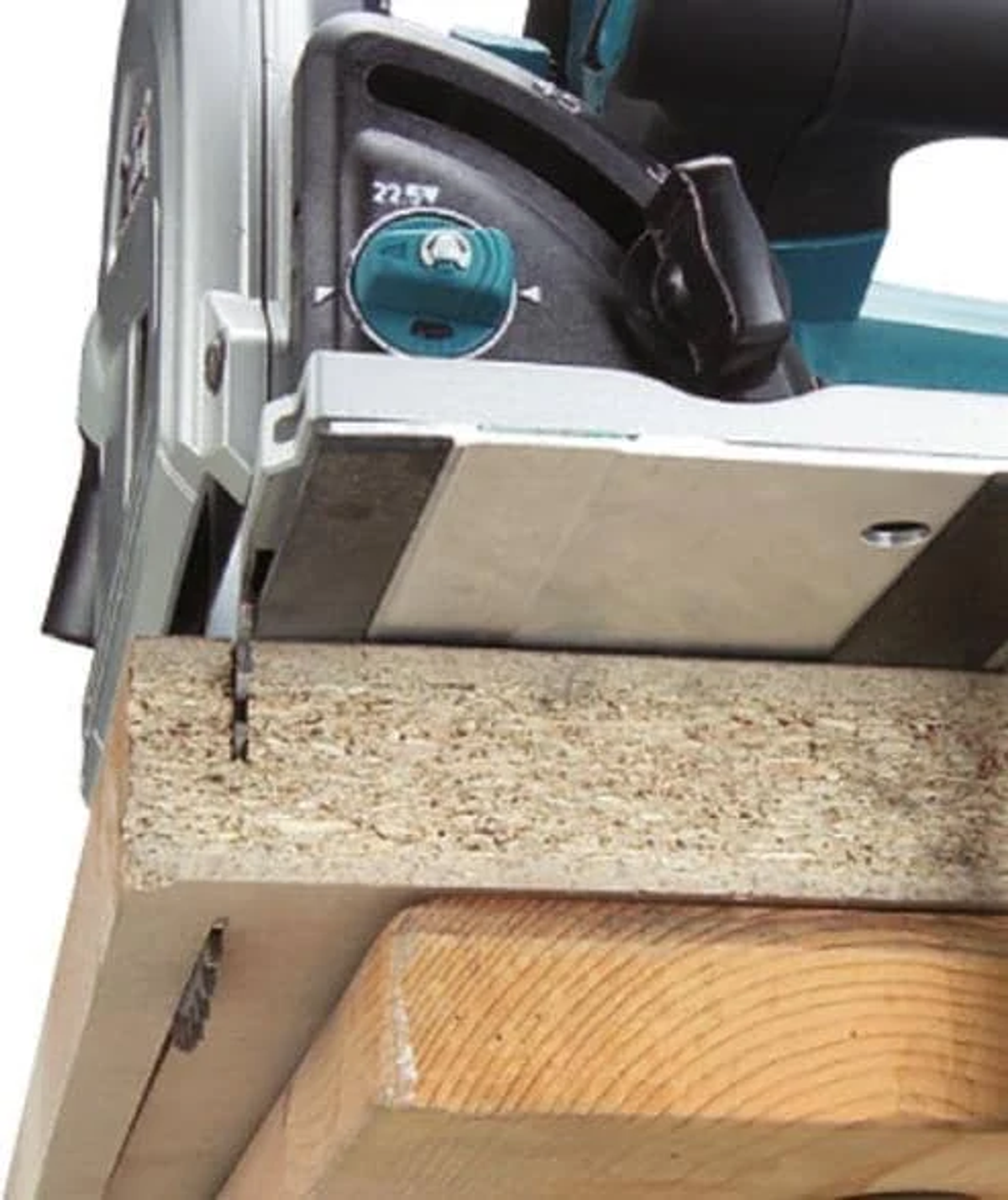 Une scie circulaire coupant une planche de bois. La scie est une Makita, coupant une planche sur une table en bois.