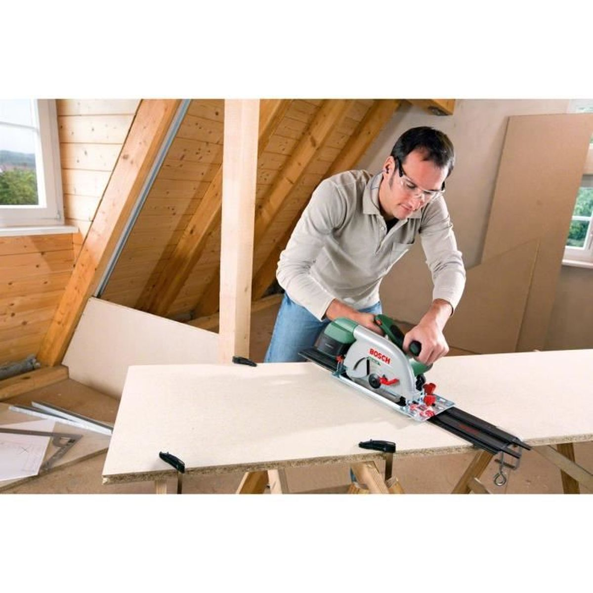 Mężczyzna używający zielono-srebrnej piły tarczowej Bosch do cięcia białej płyty.