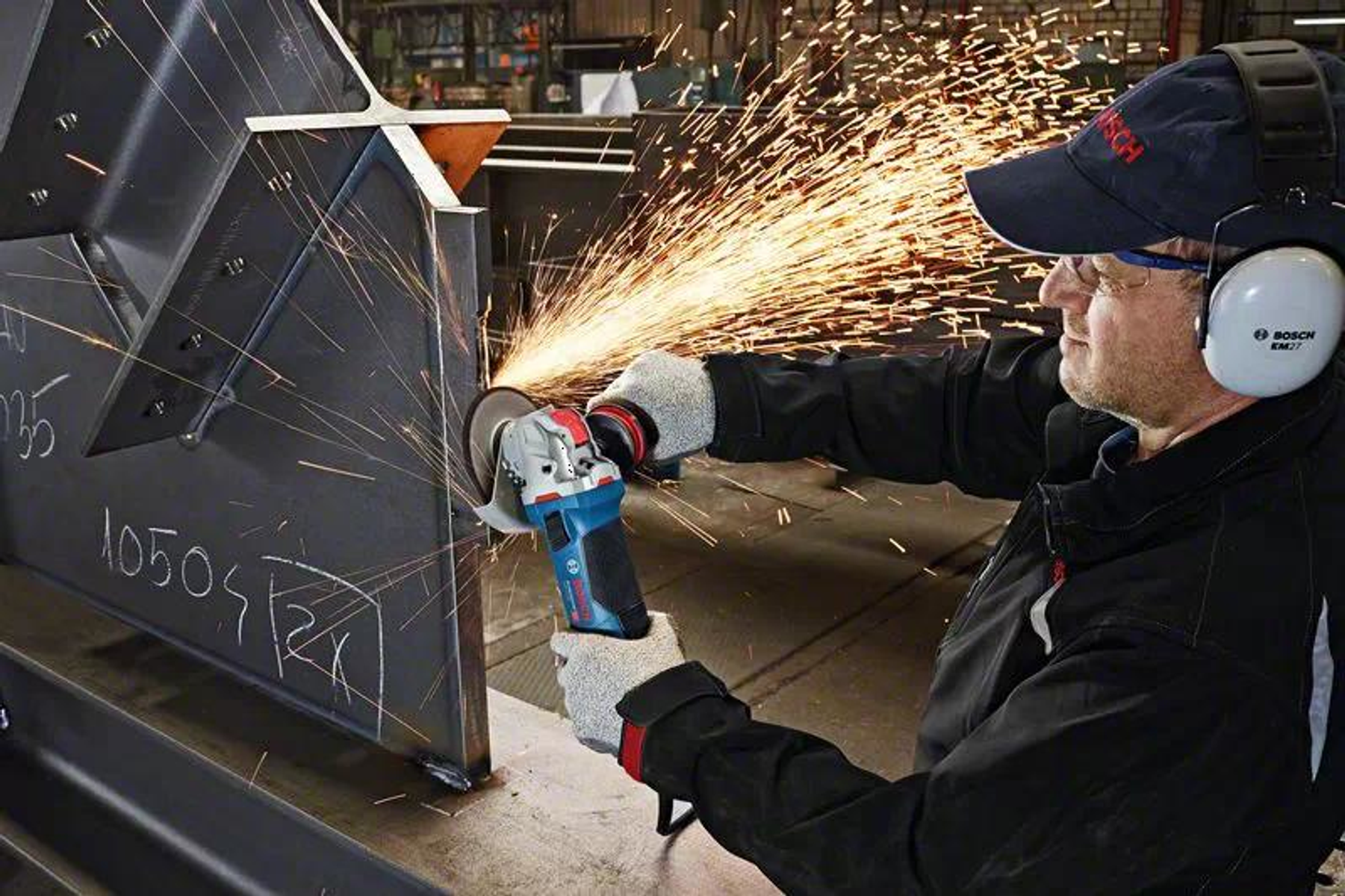 Mężczyzna używa szlifierki Bosch, tworząc iskry, nosząc okulary ochronne i ochronniki słuchu.