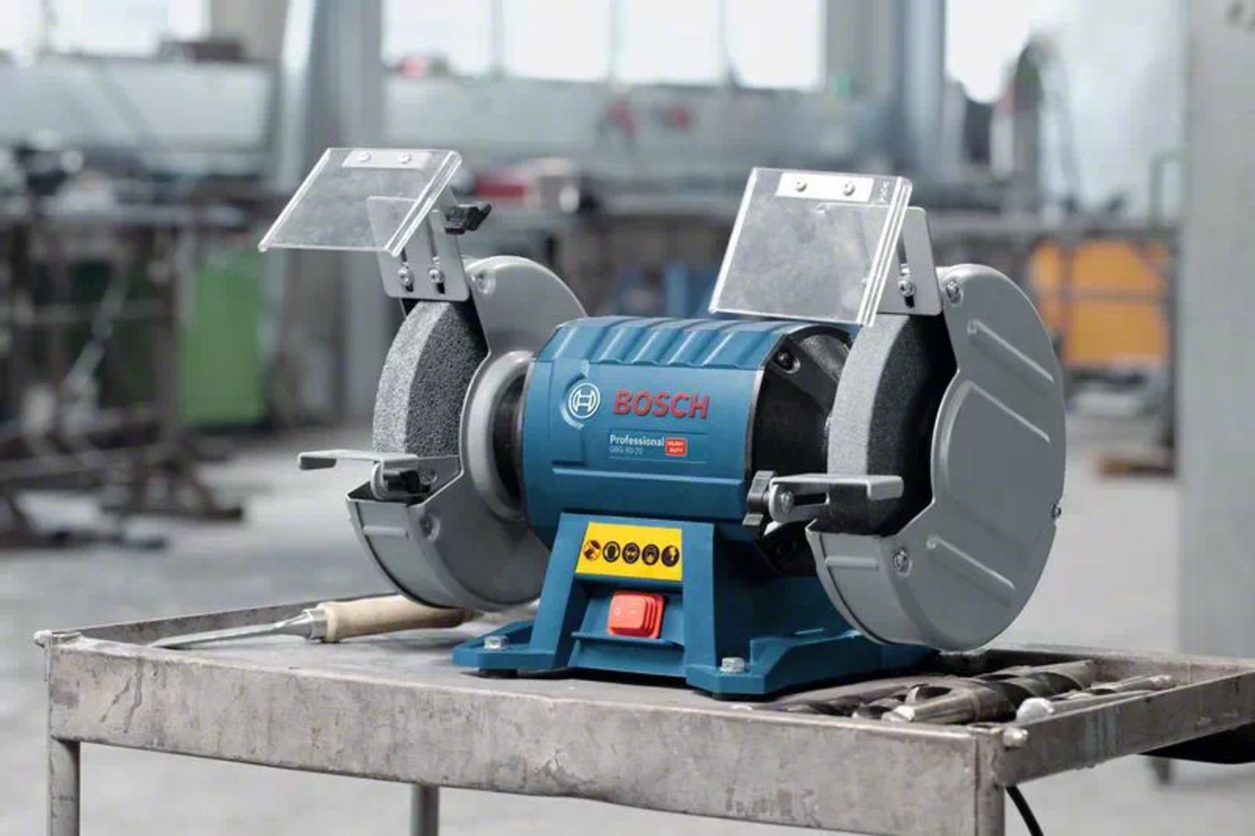 Metal bir yüzeyde bir Bosch tezgah tipi taşlama makinesi. Mavi ve gümüştür.