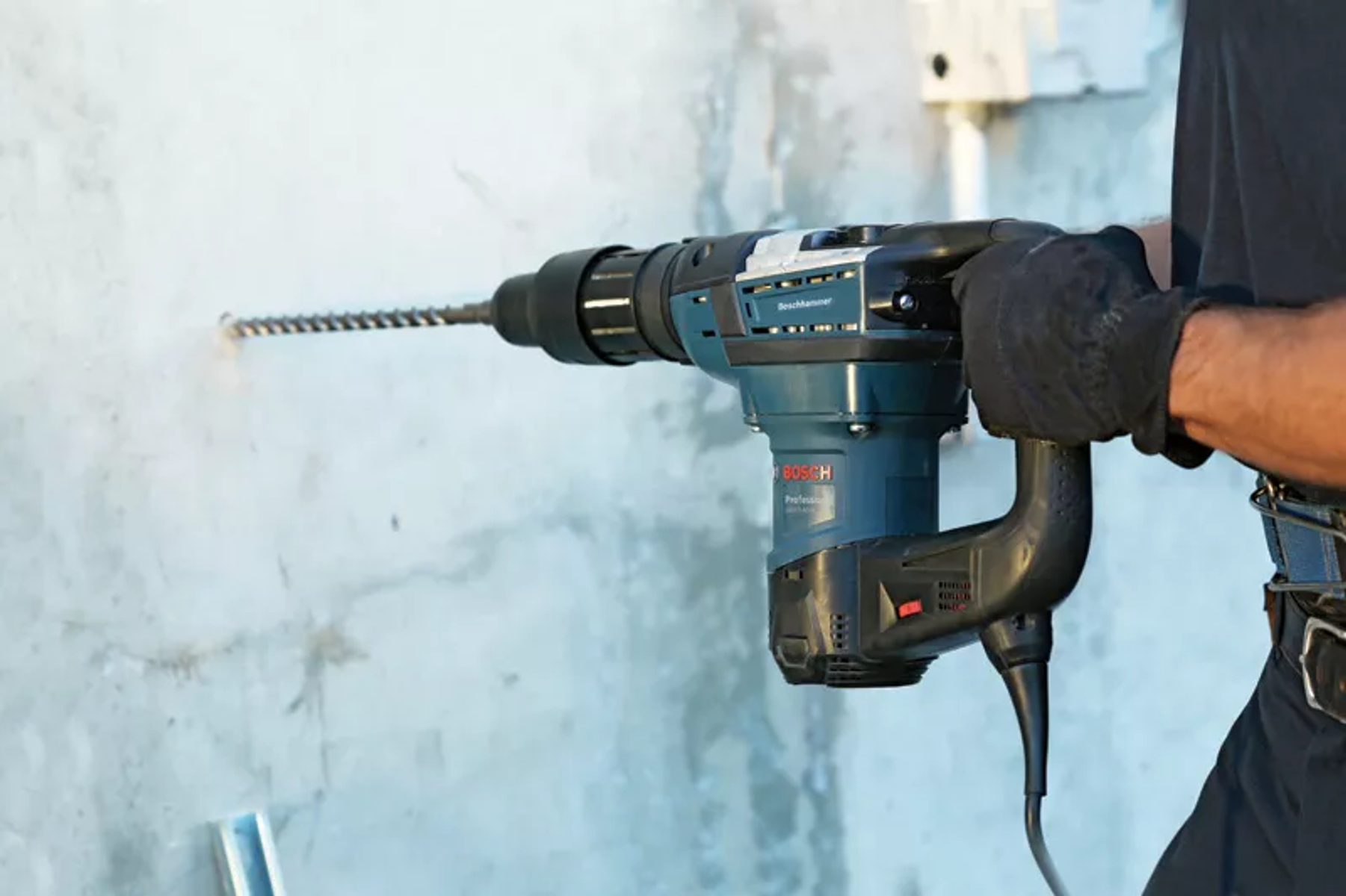 Ein Mann bohrt mit einem Bosch Bohrhammer in eine Betonwand.