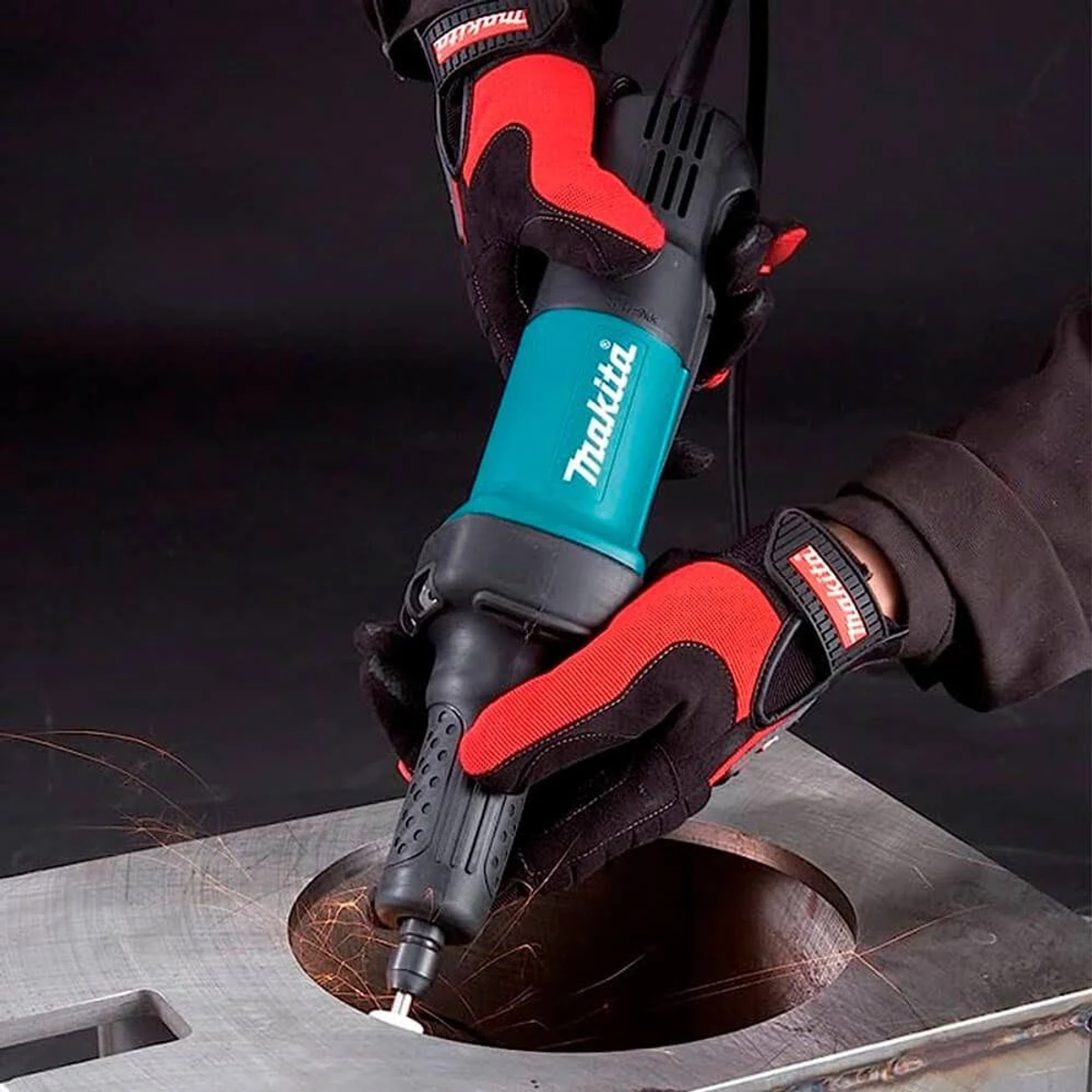 Dłonie w czerwonych rękawicach używają szlifierki do wygładzania metalu.