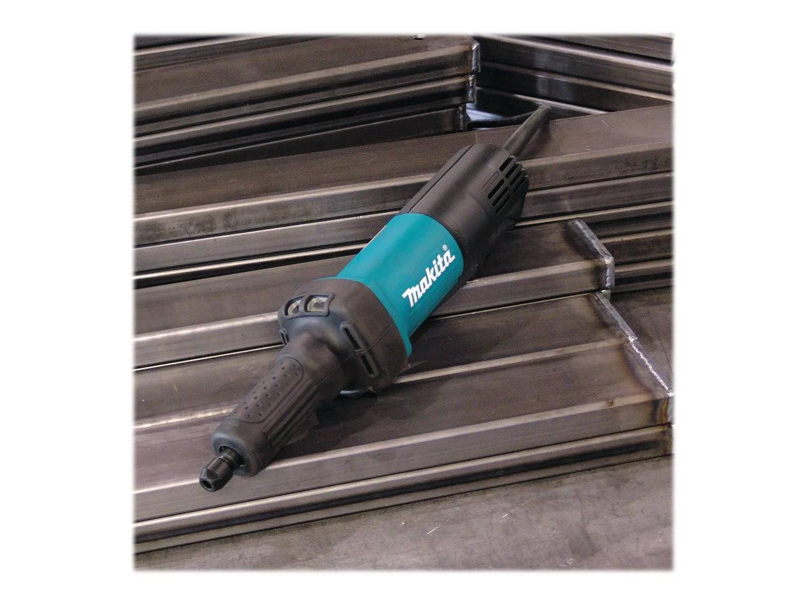 Zielono-czarna szlifierka trzpieniowa Makita na stosie metalowych prętów.