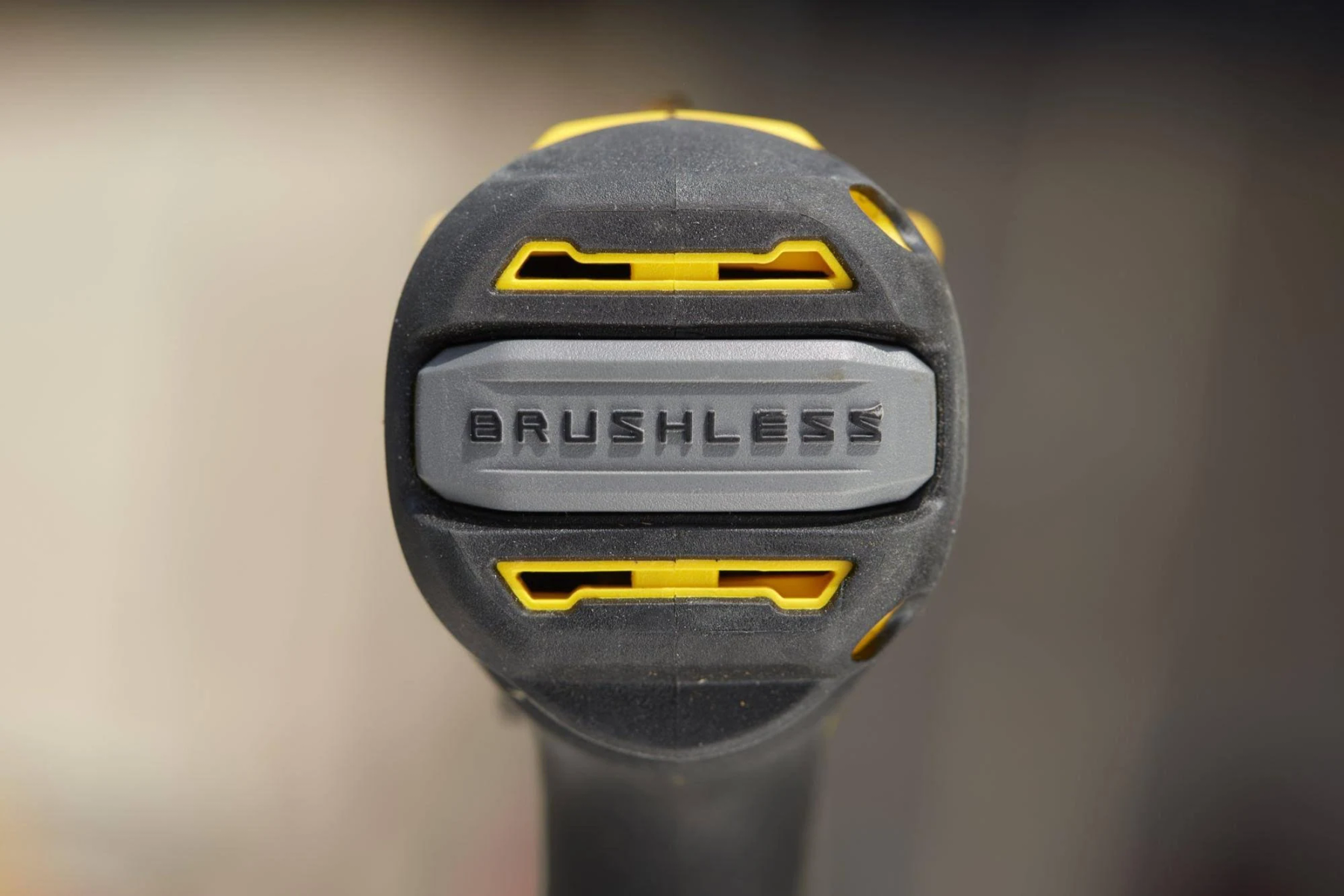 Primer plano del extremo de un taladro eléctrico negro y amarillo con la palabra 'BRUSHLESS'.