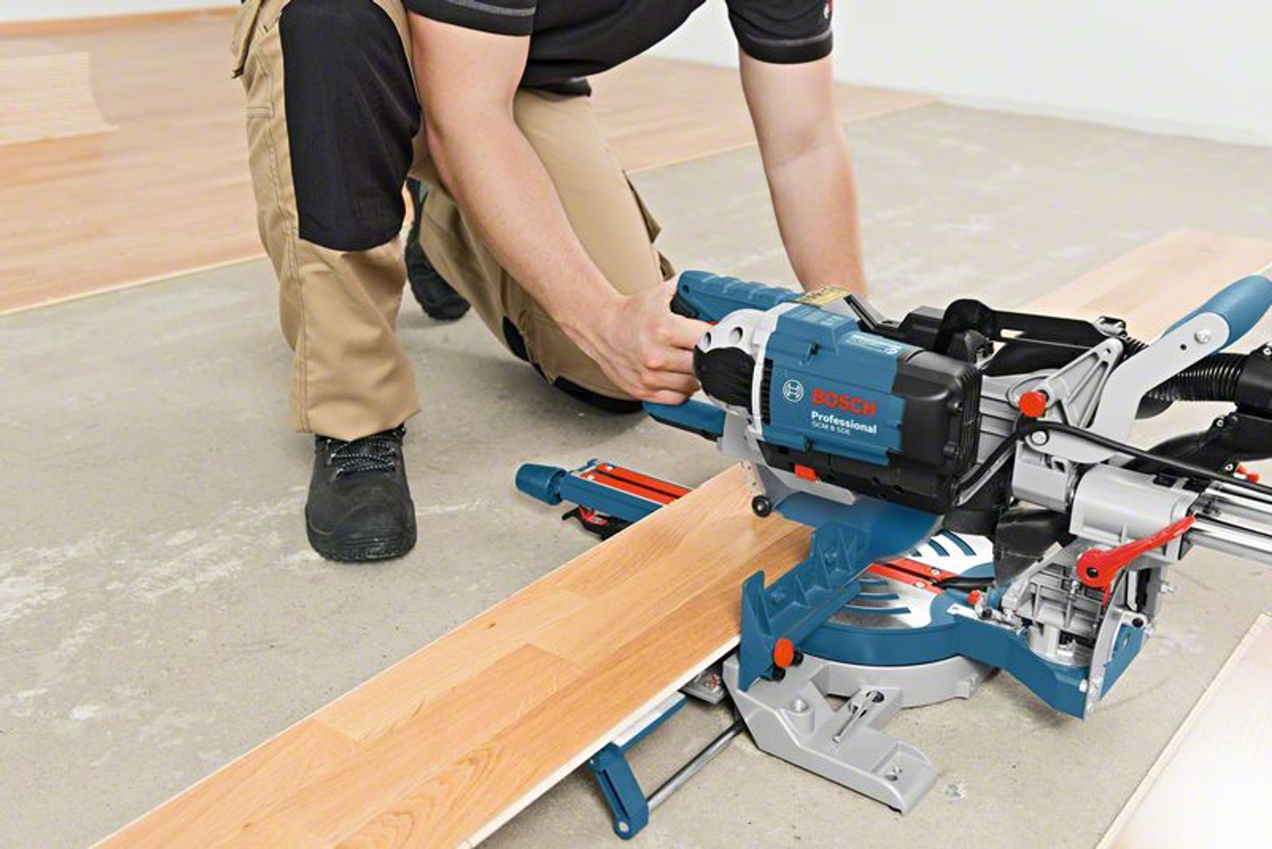 Una persona corta madera con una sierra Bosch, en un taller, con la herramienta cerca de la madera.